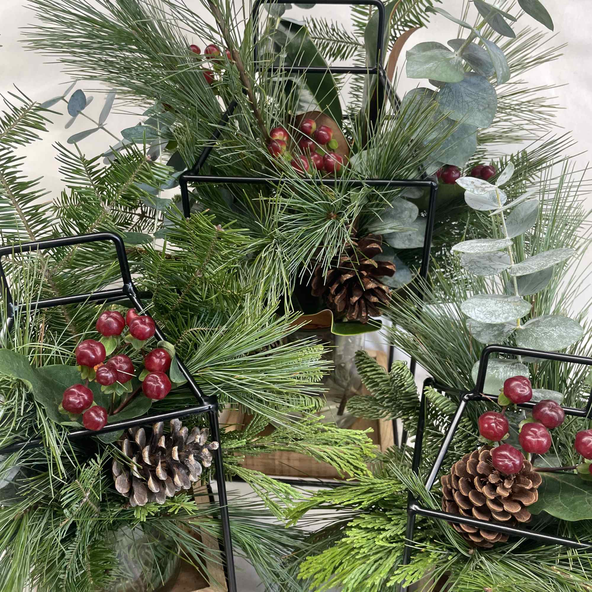 A metal lantern with a wooden base- enjoy now filled with greenery