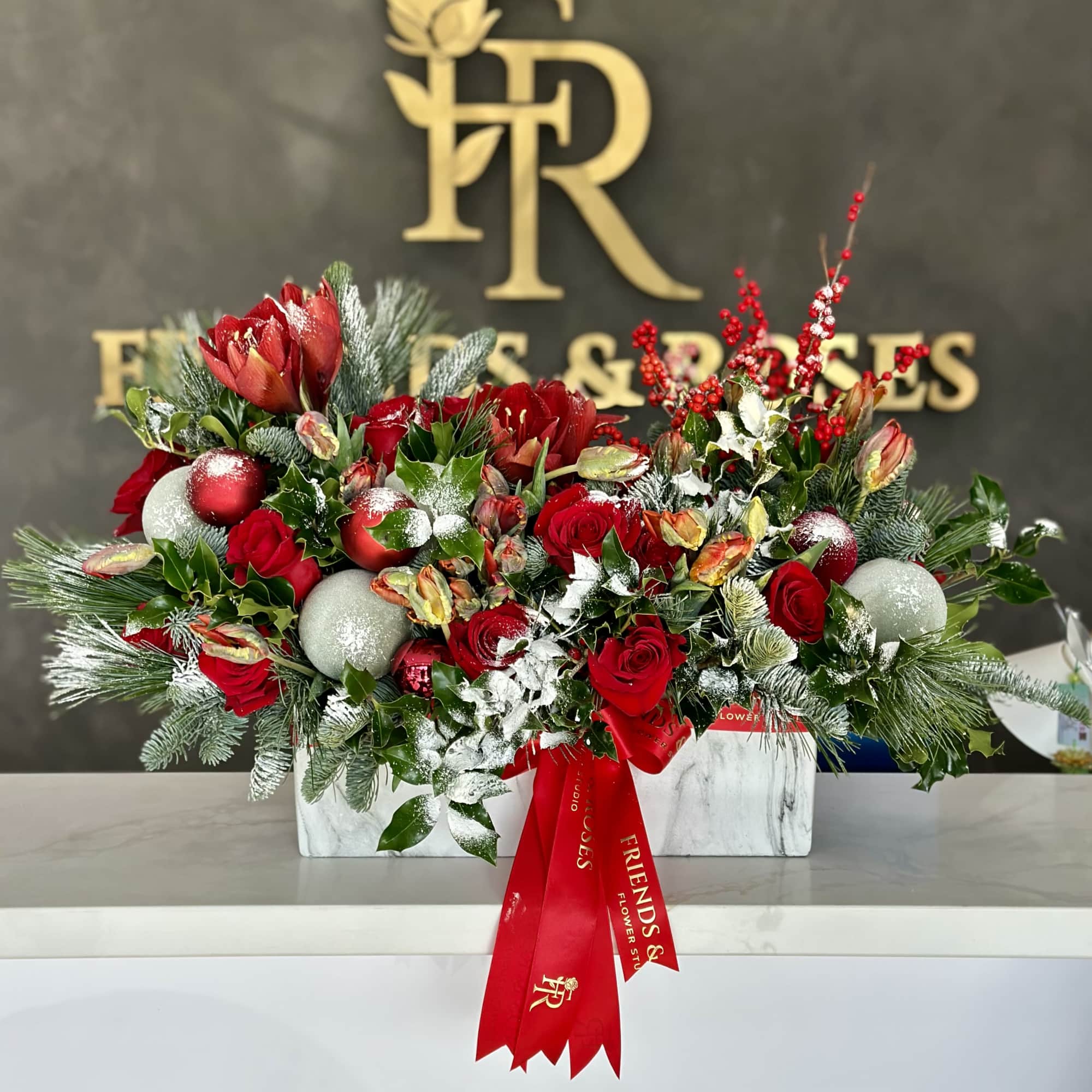 A festive Christmas arrangement featuring red roses and fresh tulips, accented with