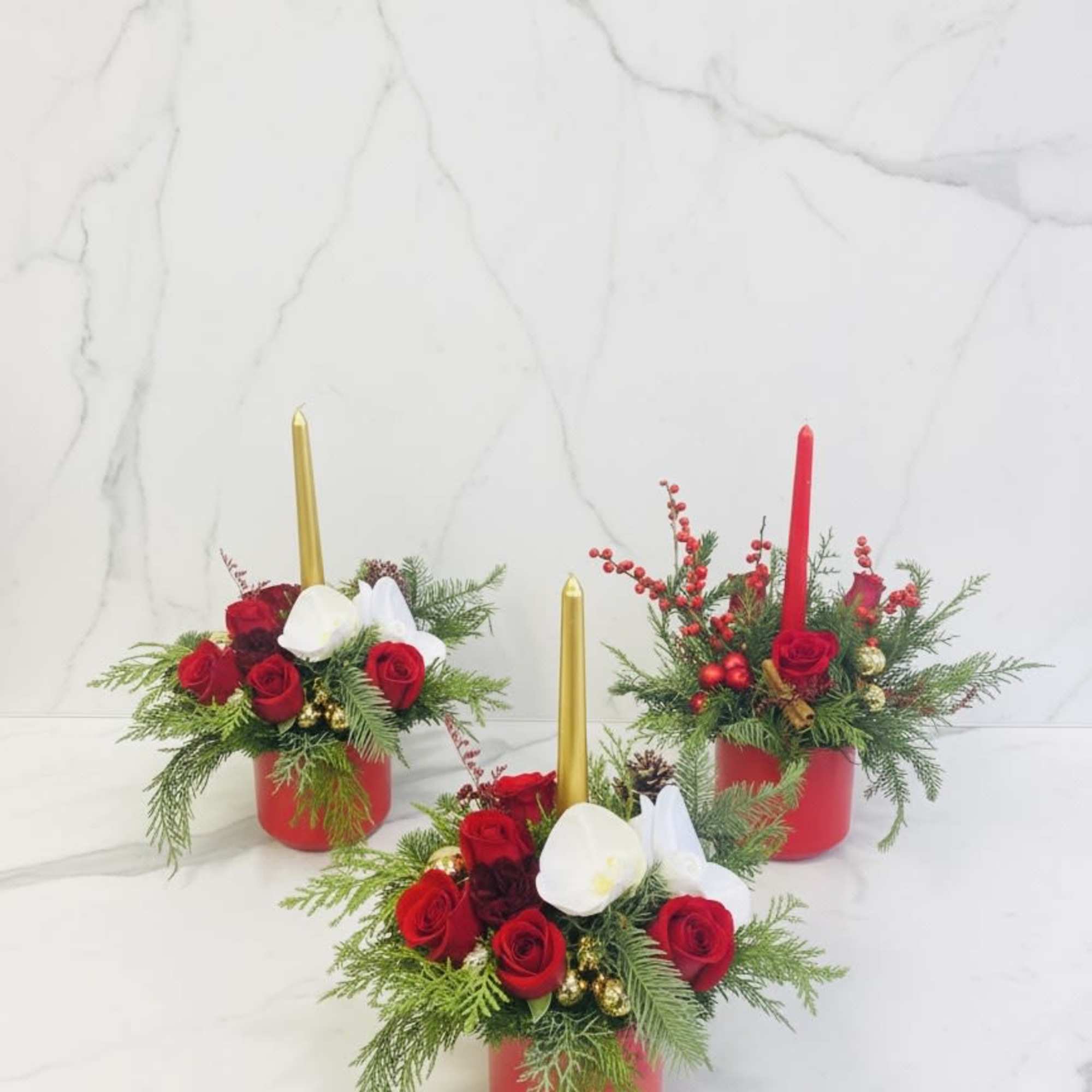 A charming holiday floral arrangement featuring fresh red roses, seasonal evergreens, decorative