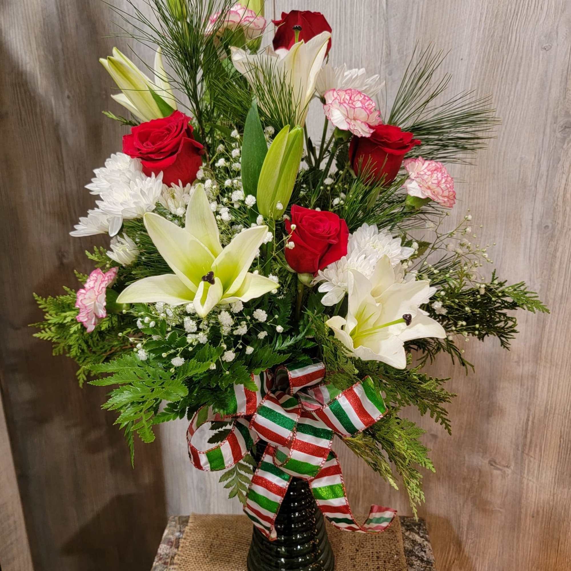 Beautiful holiday vase arrangement with white lilies, red roses, and peppermint carnations