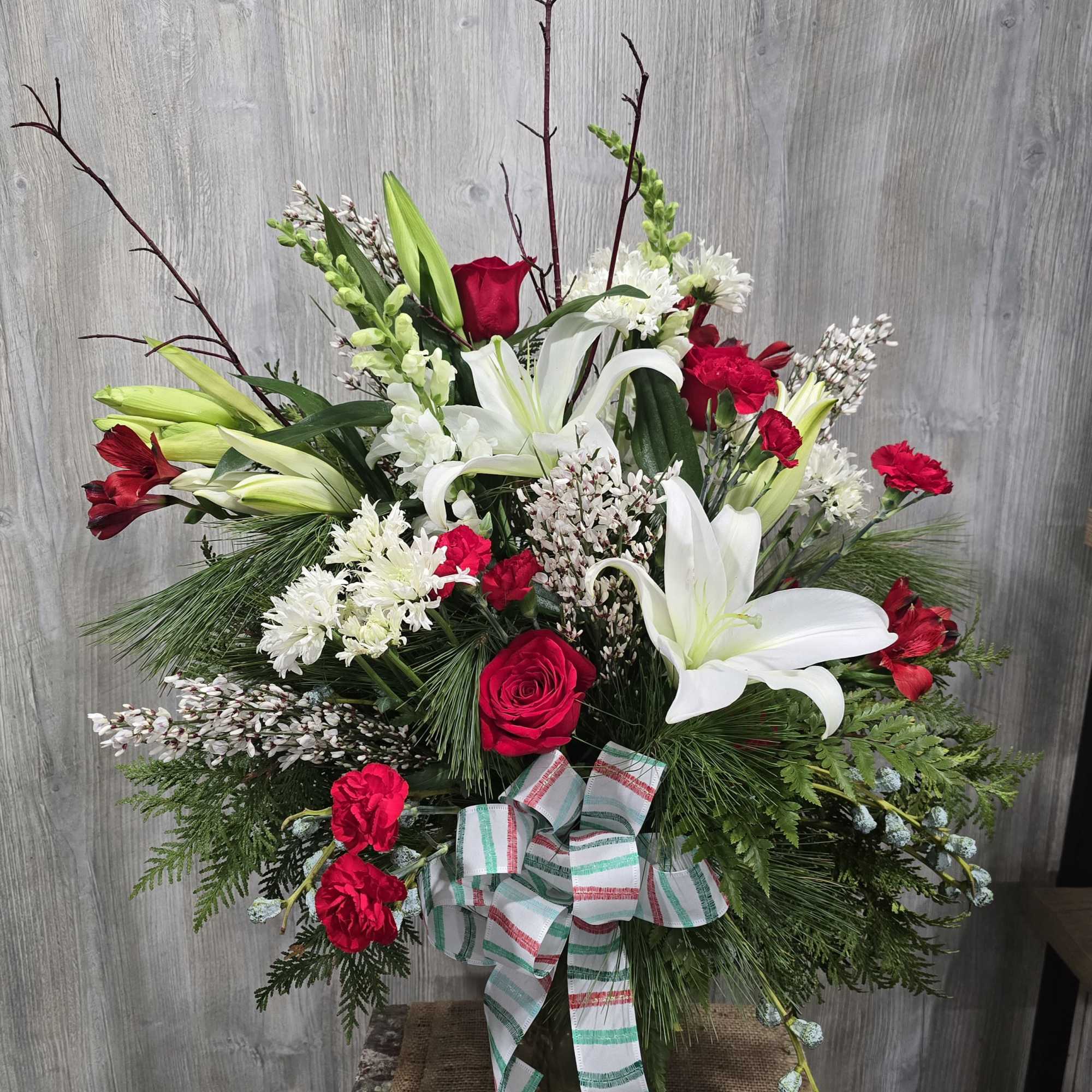 Beautiful holiday vase arrangement with white lilies, red roses, and peppermint carnations