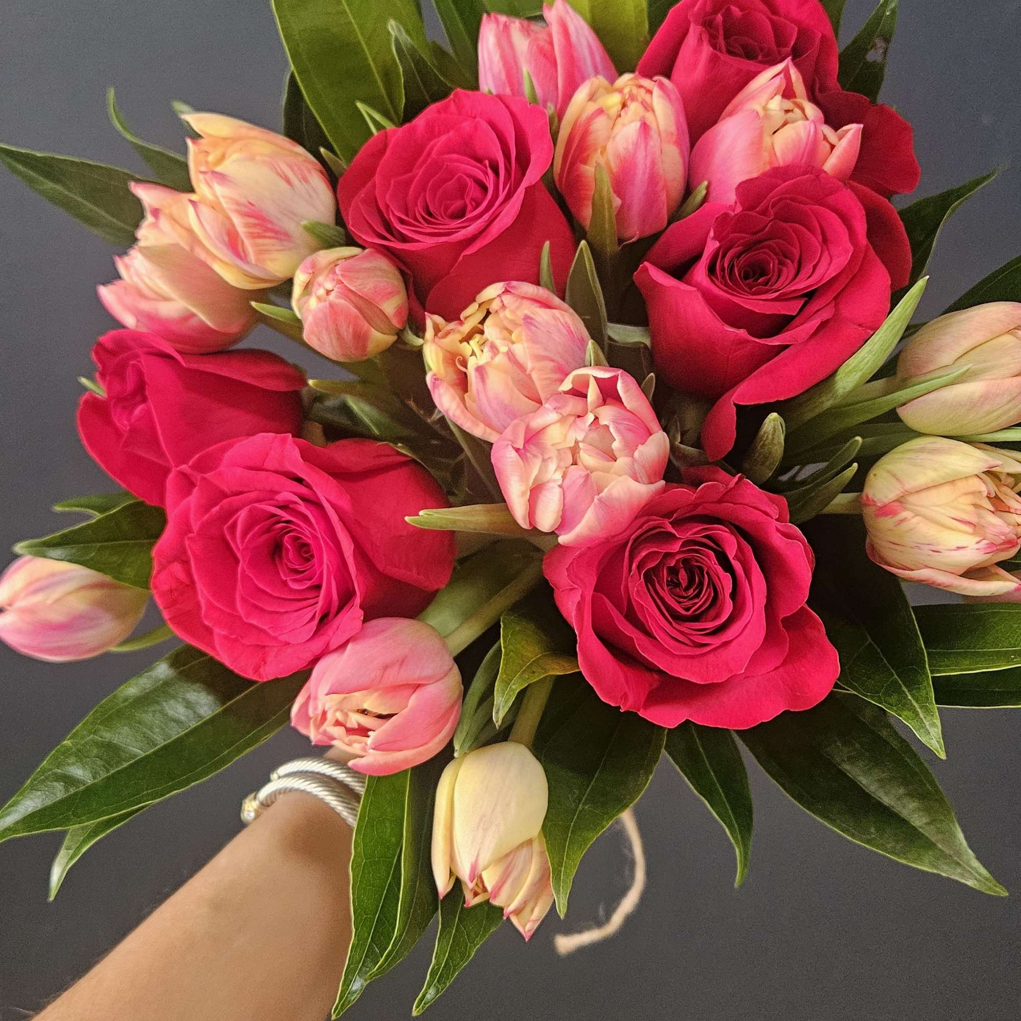 Beautiful hand-tied bouquet of a six red roses and ten pink tulips