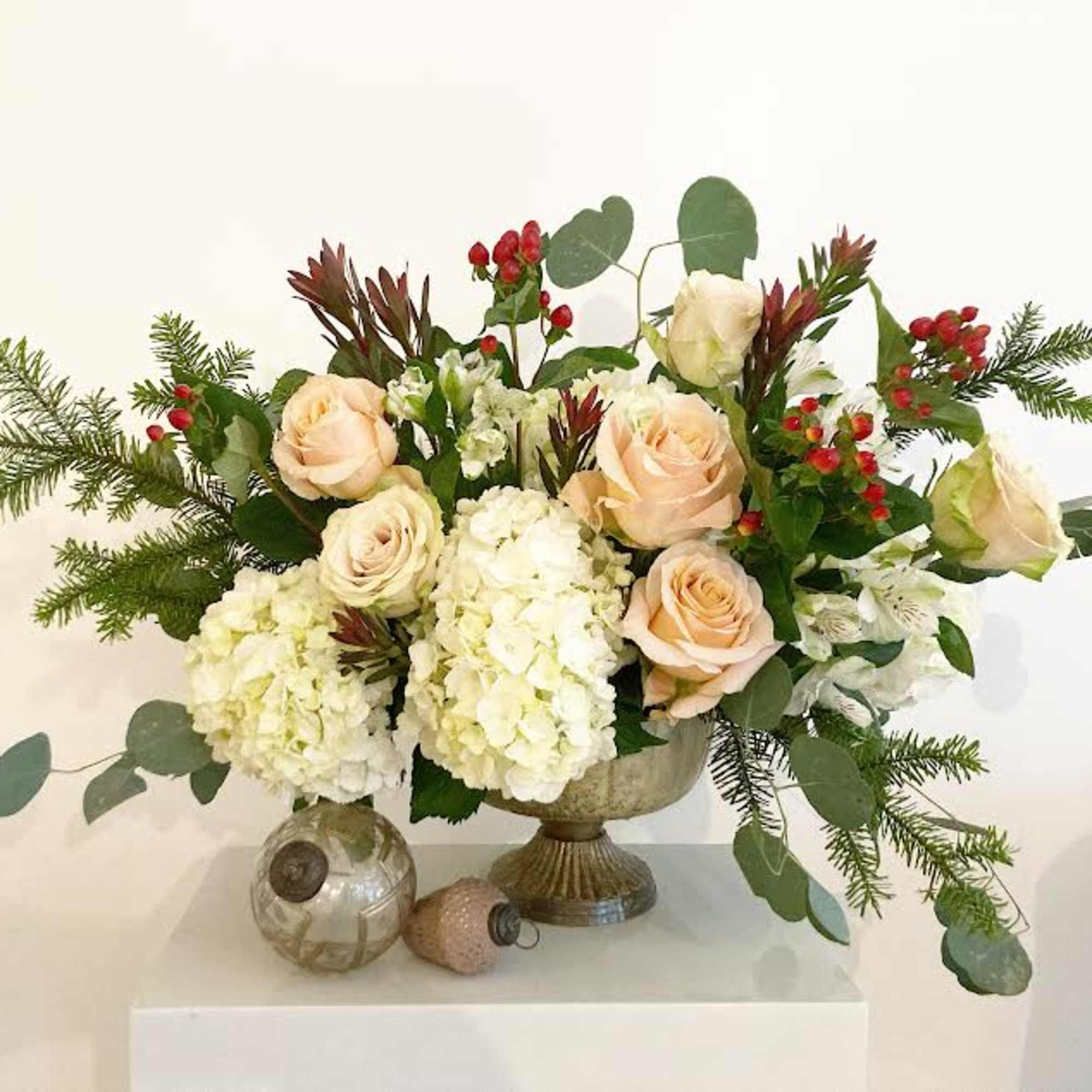 Fluffy white hydrangeas, peach and nude garden roses, winter greens and red