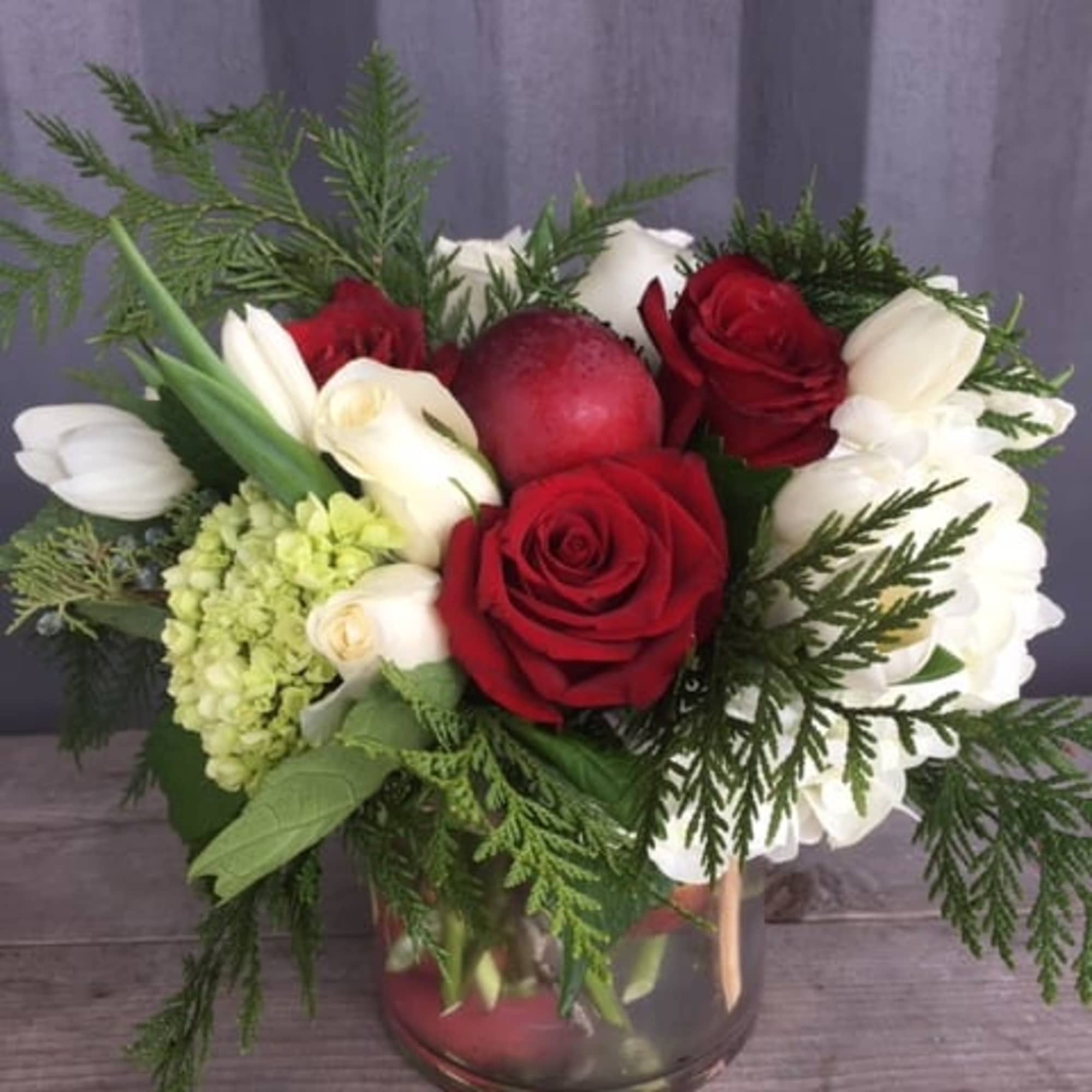 Holiday flower arrangement with red/ whit/ green flowers and red apples 