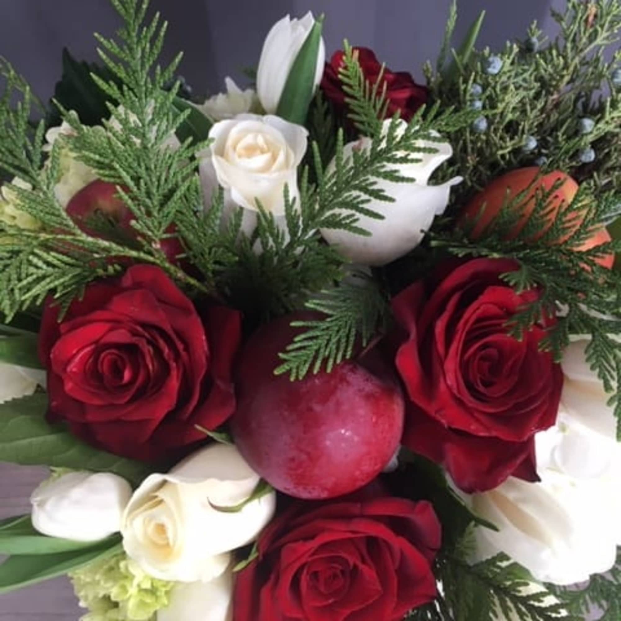 Holiday flower arrangement with red/ whit/ green flowers and red apples 
