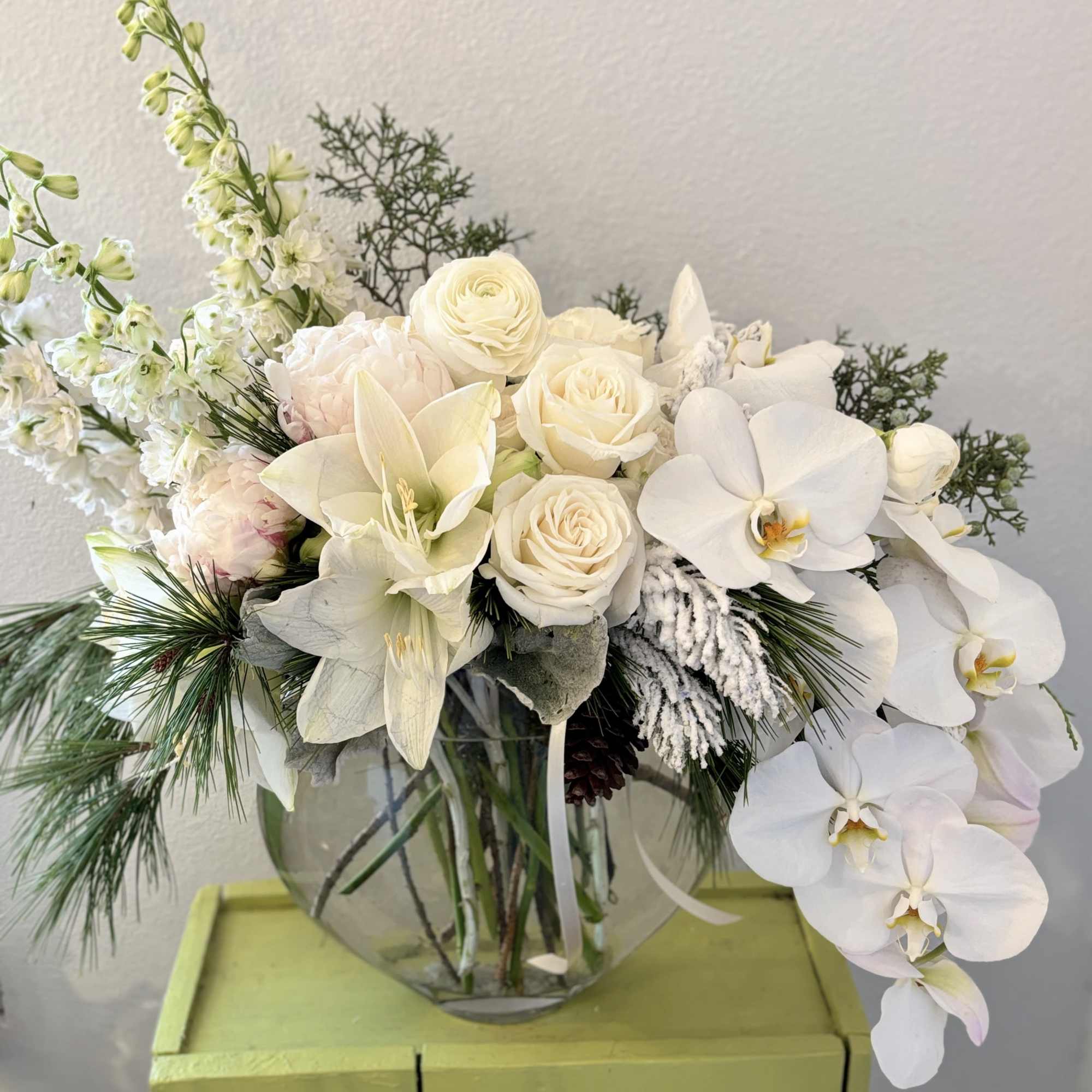 A beautiful lush arrangement featuring premium flowers with accents of winter foliage.