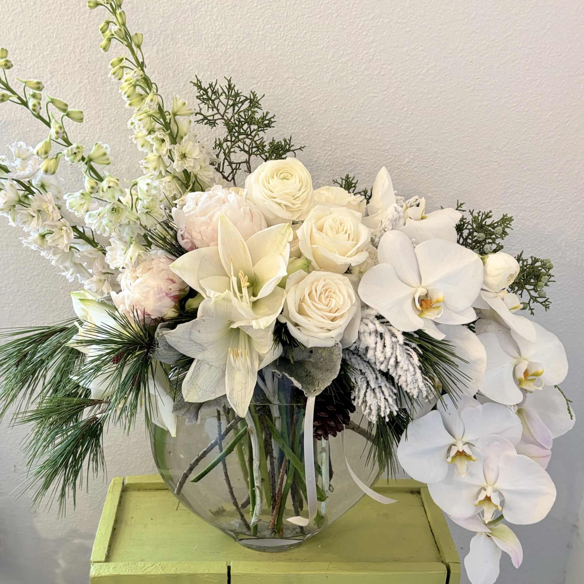 A beautiful lush arrangement featuring premium flowers with accents of winter foliage.