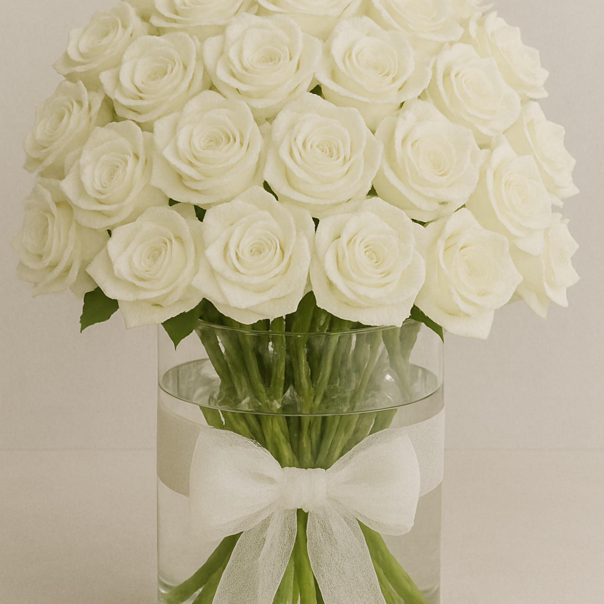 Premium white roses in a glass vase with a decorative ribbon.