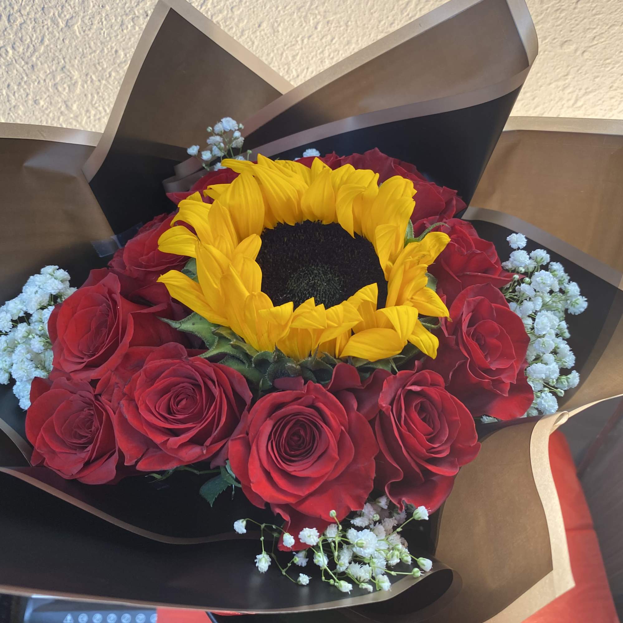 12 Red roses and a Center Sunflower with baby&rsquo;s breath surrounding them