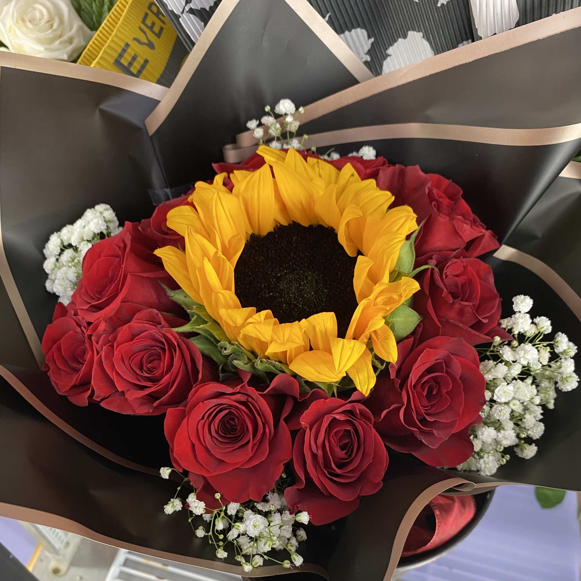 12 Red roses and a Center Sunflower with baby&rsquo;s breath surrounding them