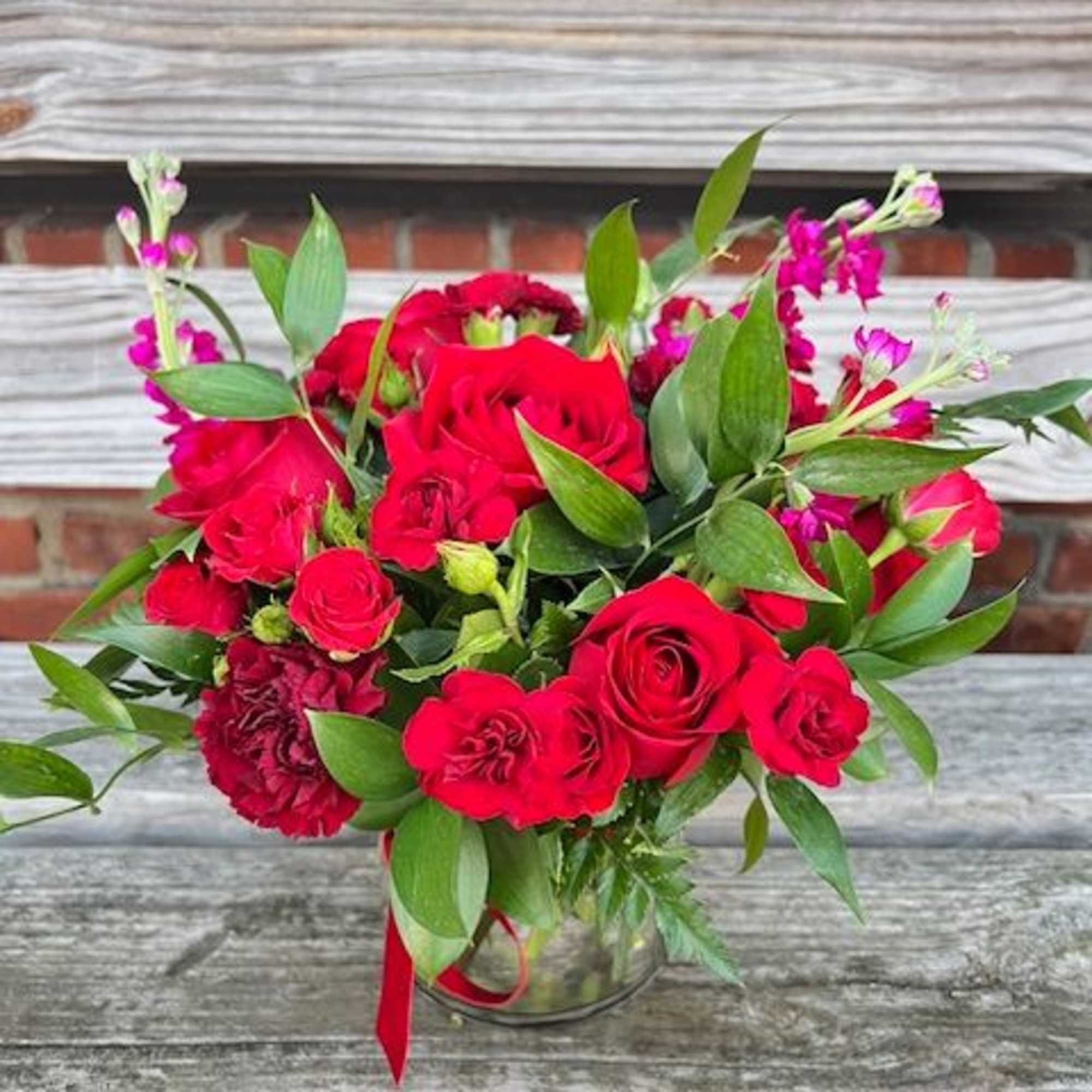 An all red arrangement using roses, carnations, stock and greenery in a