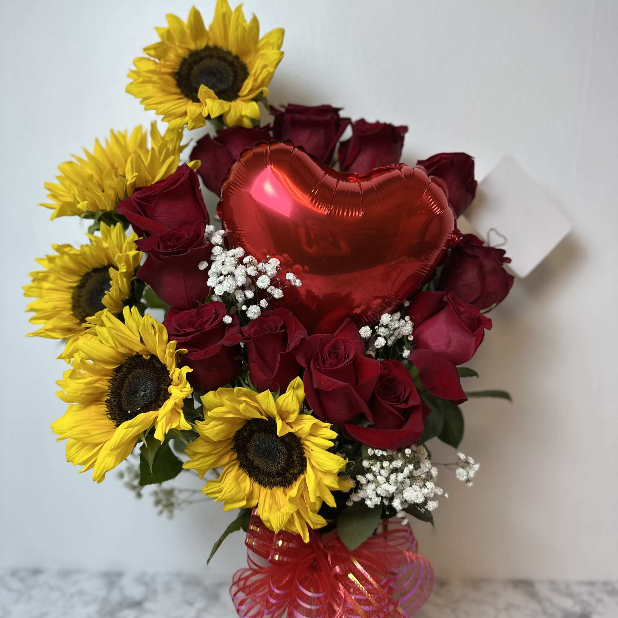 Floral arrangement with 13 red roses, 5 sunflowers, and 1 heart-shaped balloon