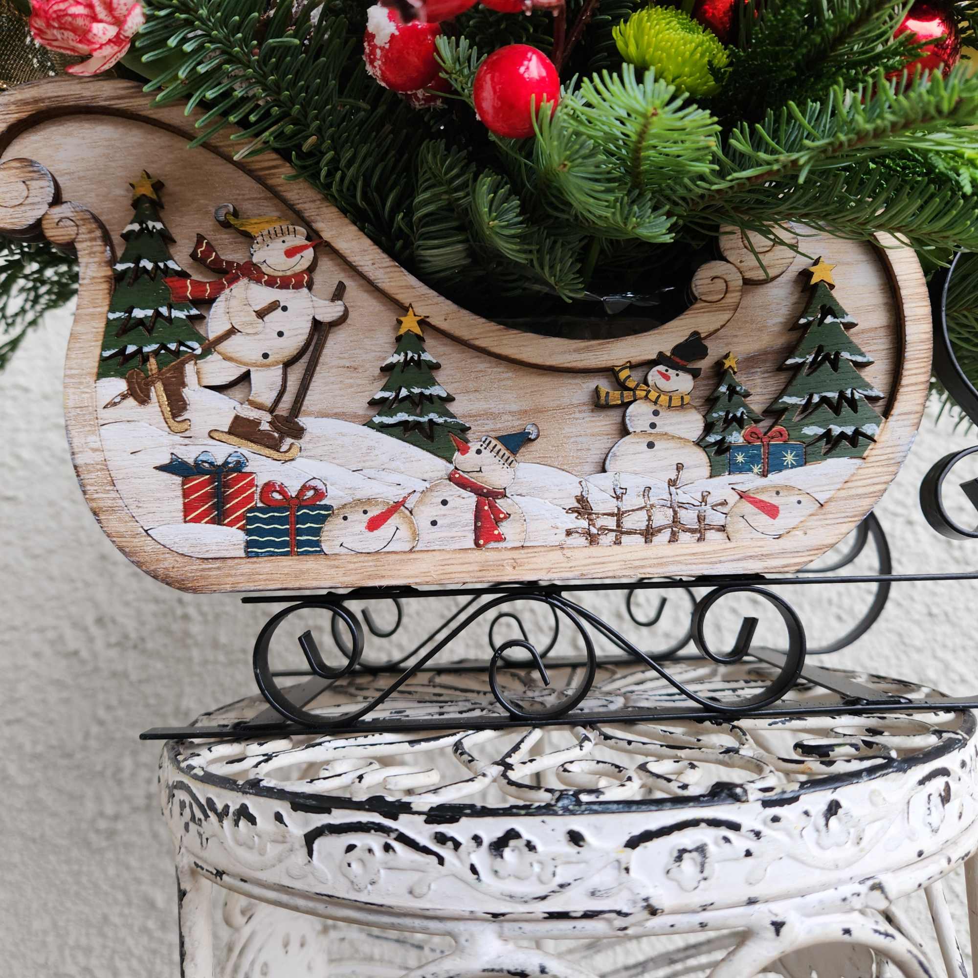 A beautiful rustic snowman sleigh designed with lots of winter evergreens red