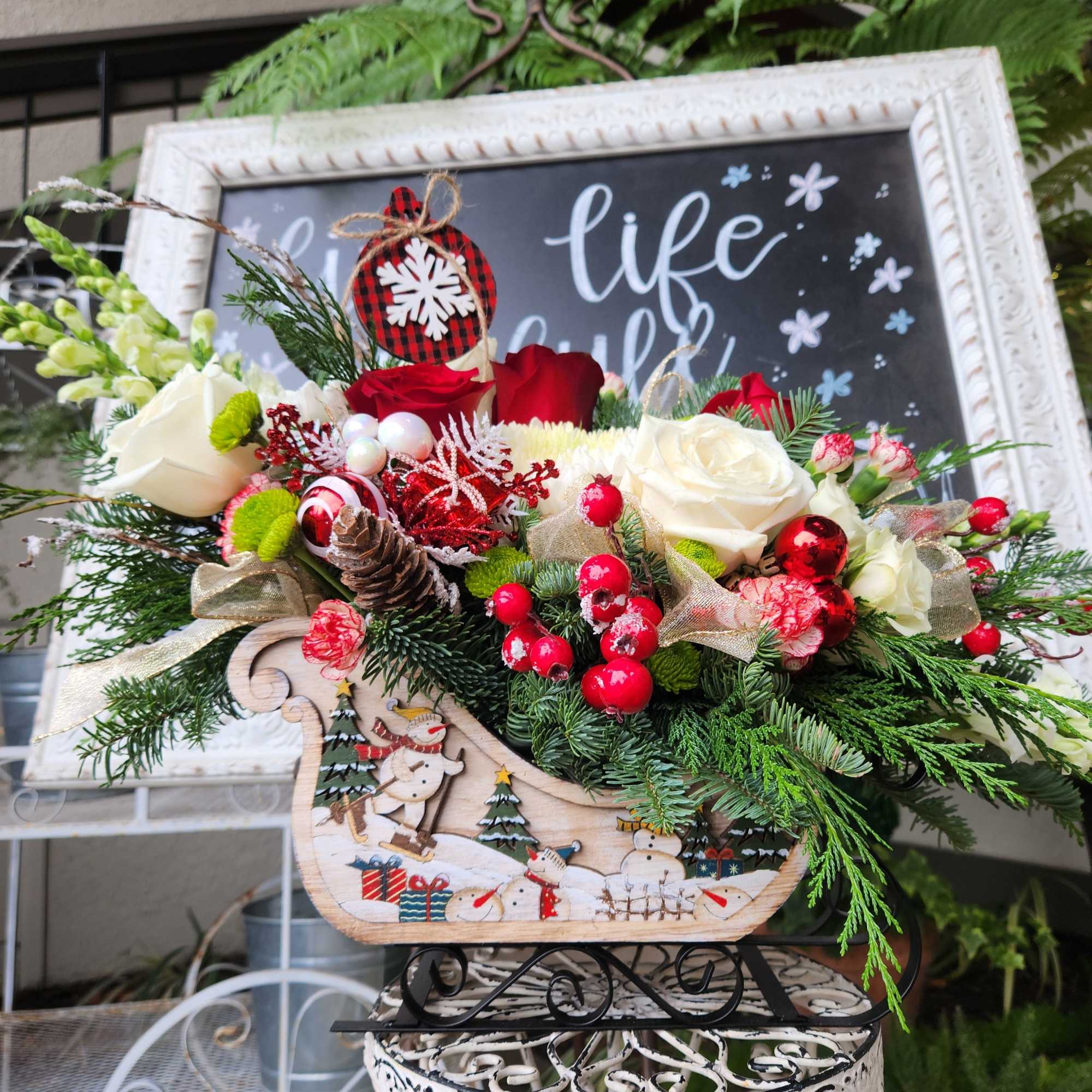 A beautiful rustic snowman sleigh designed with lots of winter evergreens red