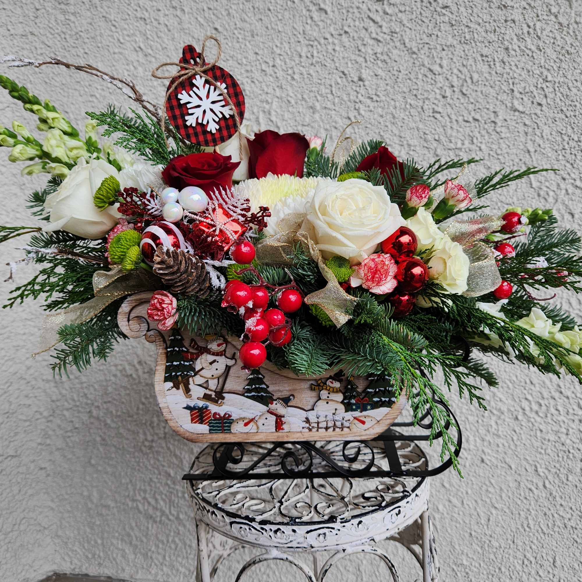 A beautiful rustic snowman sleigh designed with lots of winter evergreens red