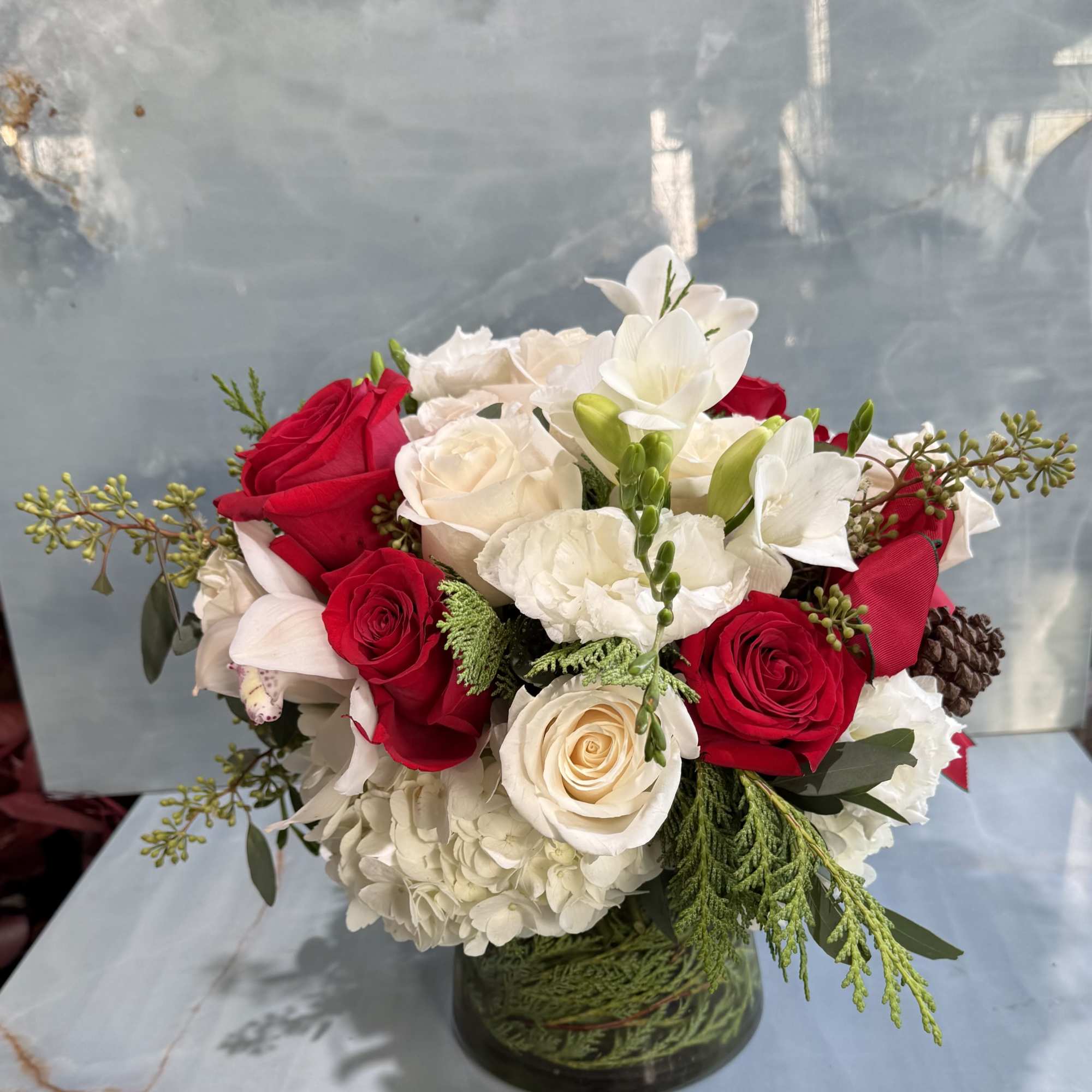 This floral arrangement is elegant, classic, and warmly festive. A lush mix