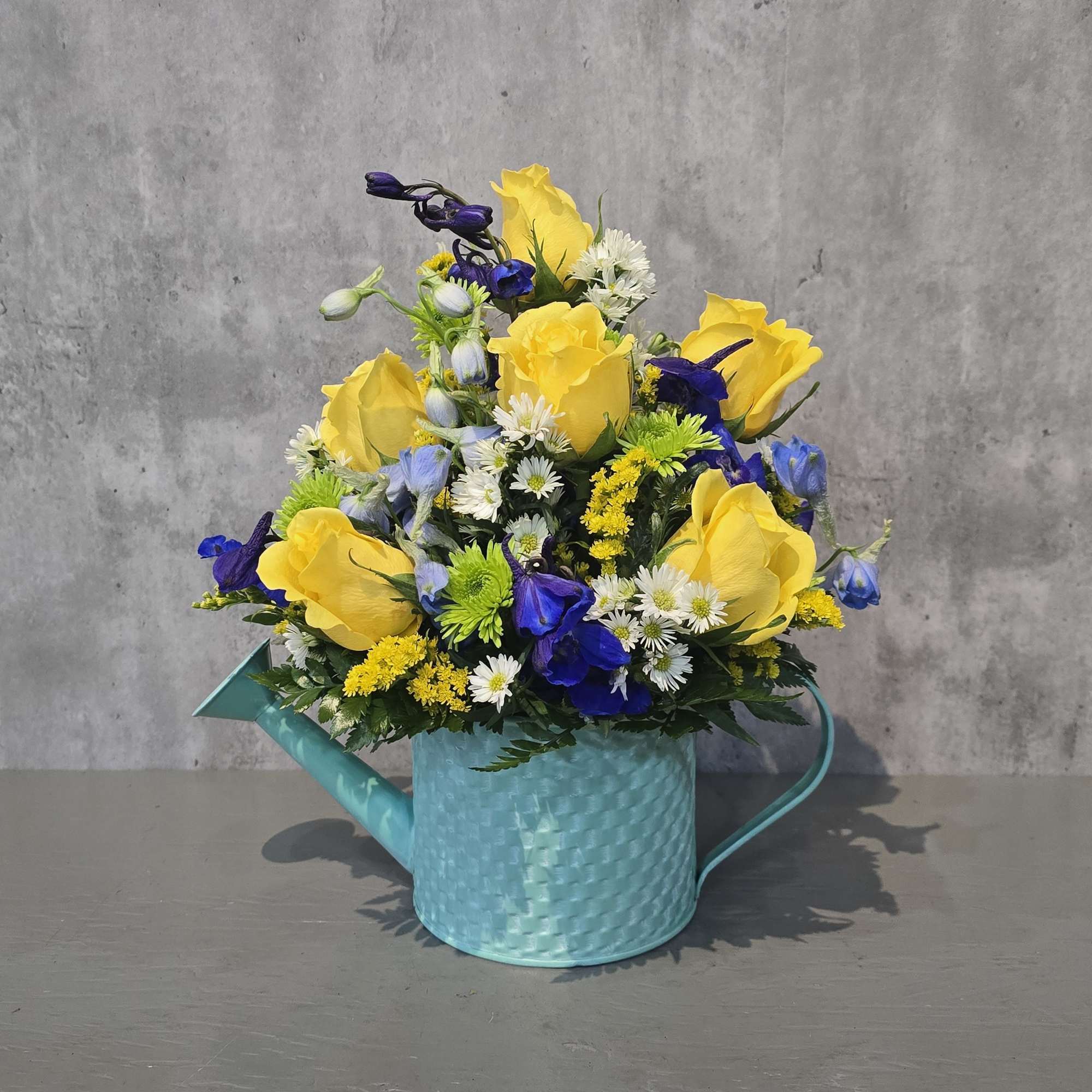 Aqua metal watering can filled with beautiful flowers