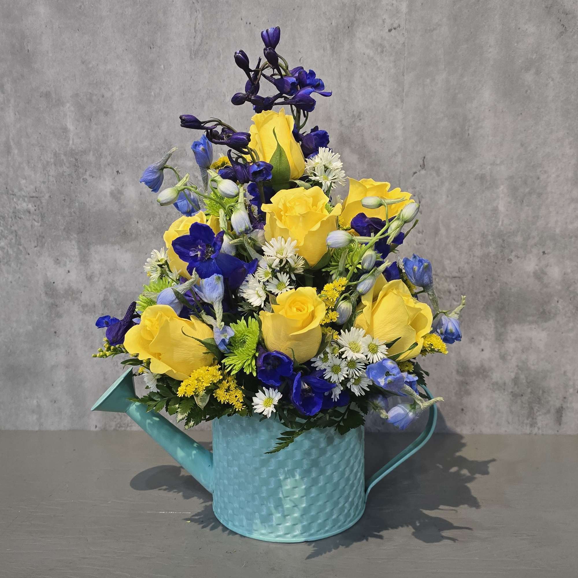 Aqua metal watering can filled with beautiful flowers