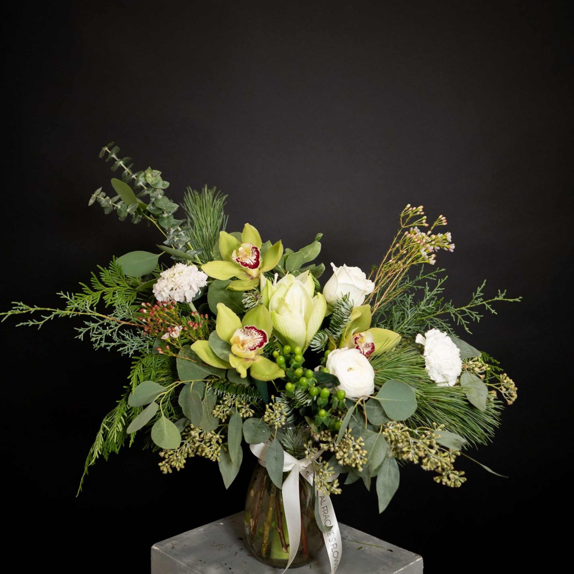 This elegant winter arrangement captures the serene beauty of a snow-dusted landscape.