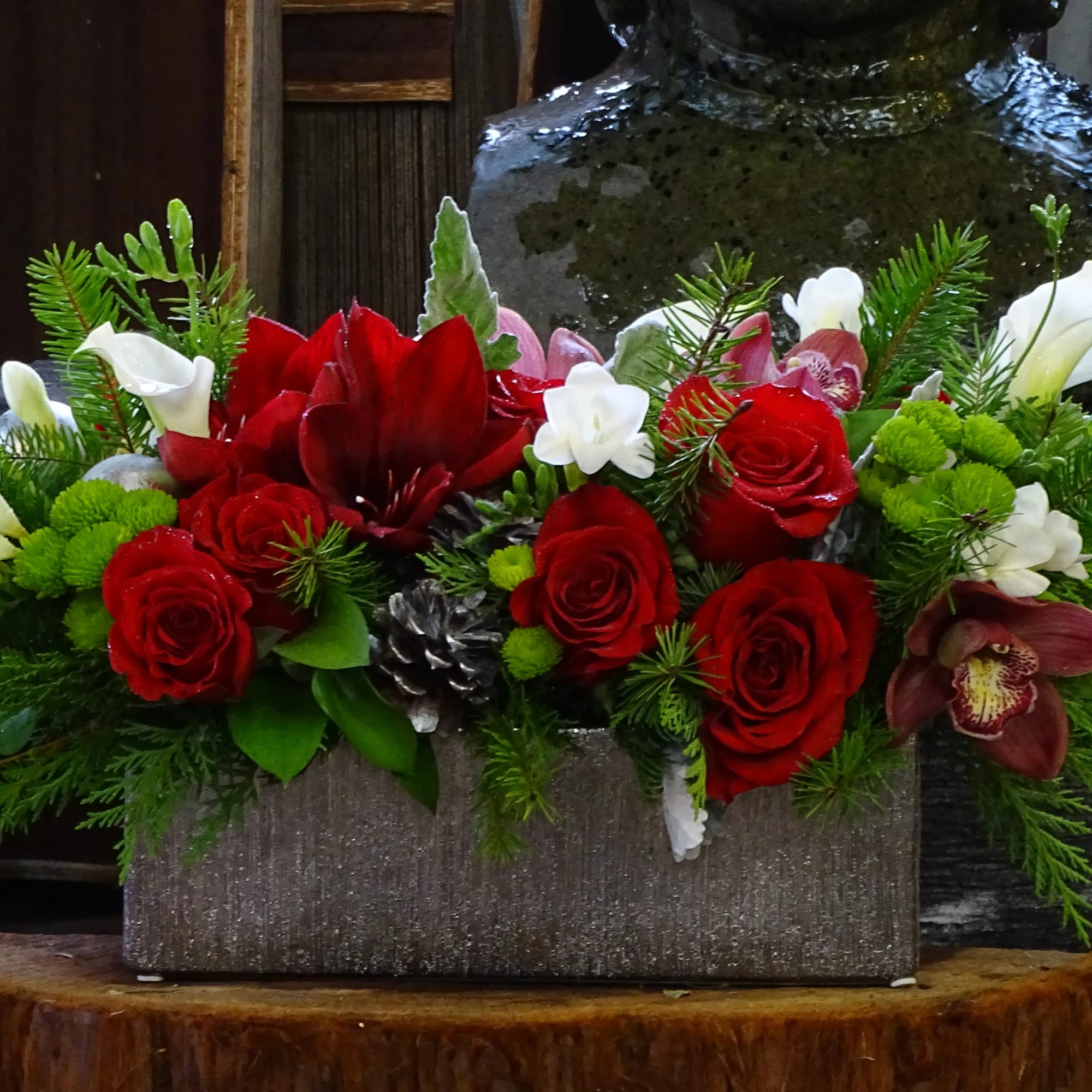 A low, elongated centerpiece overflowing with velvety red rose, creamy white blooms