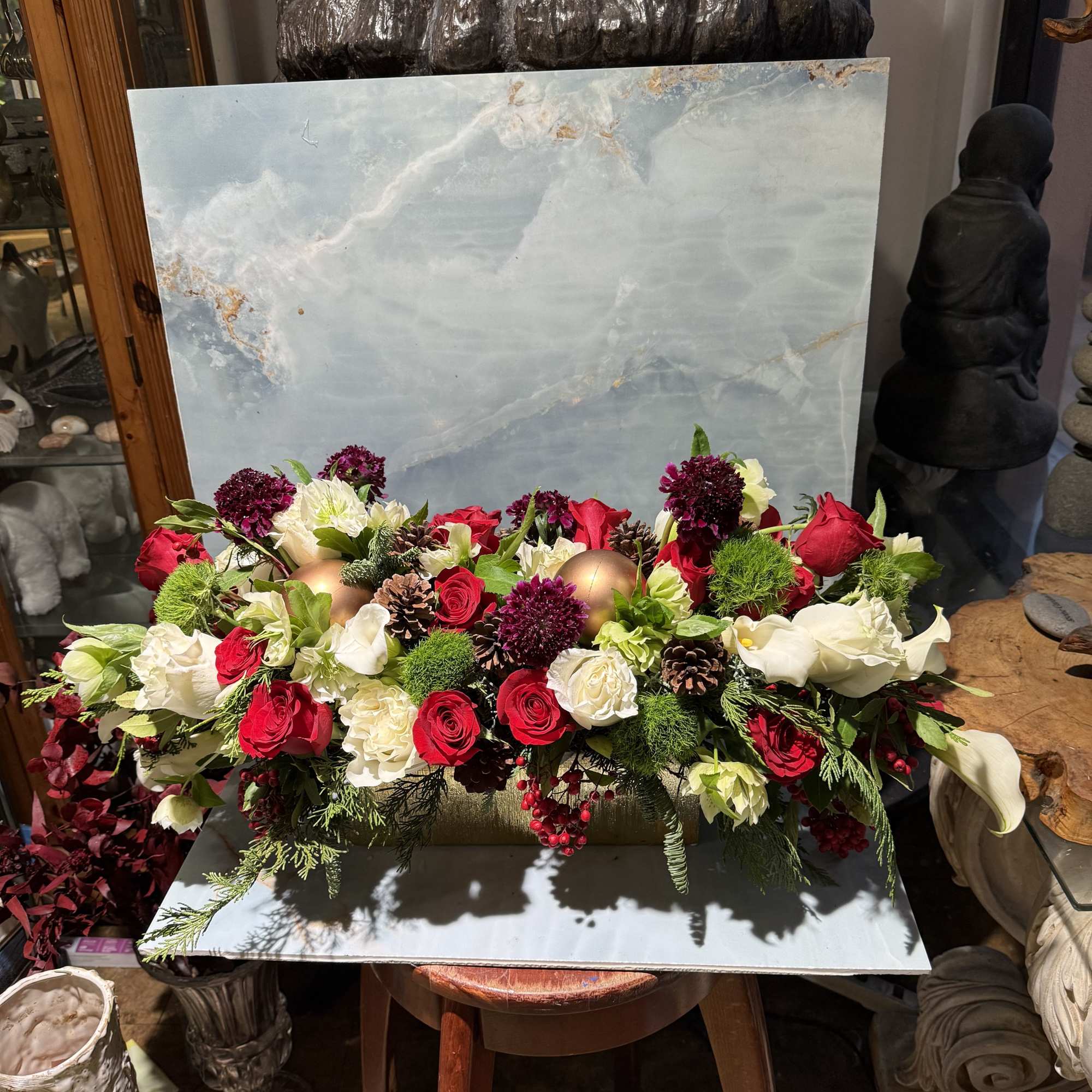 A low, elongated centerpiece overflowing with velvety red rose, creamy white blooms