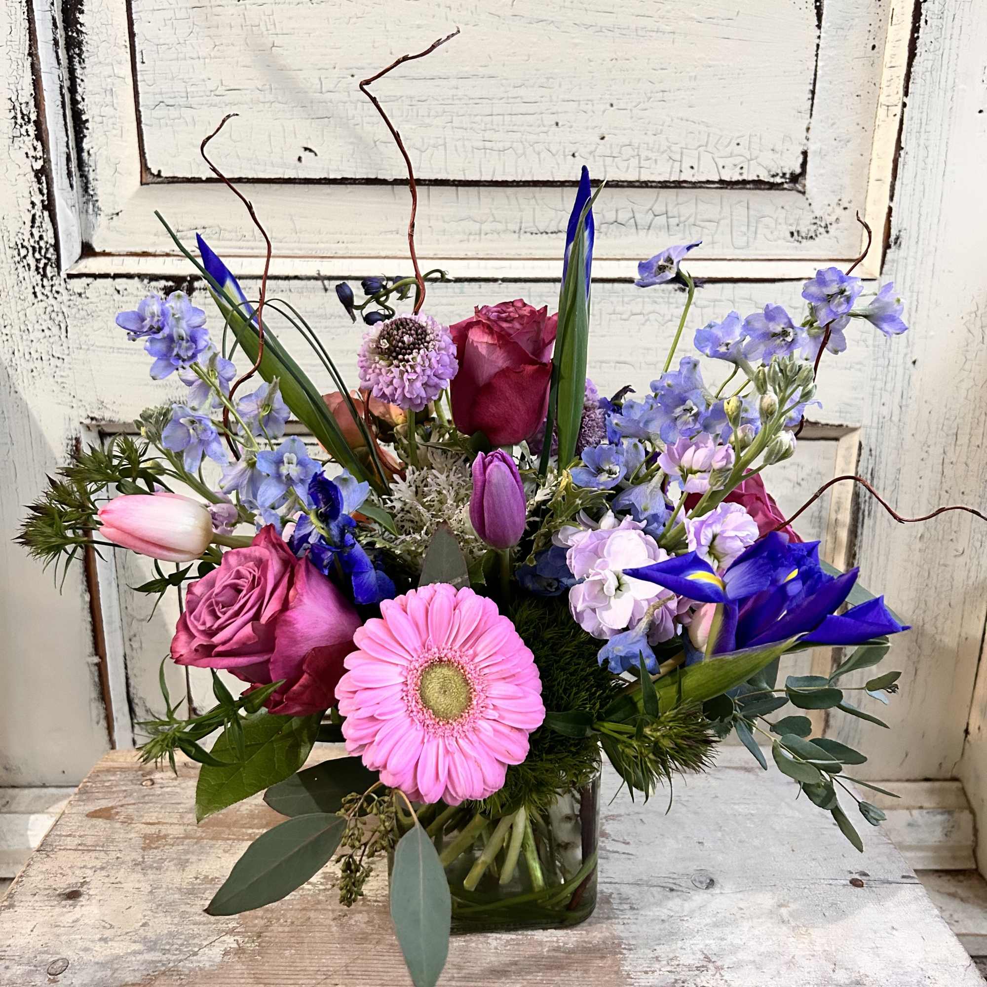 A curly willow or grass lined 5" glass cube is arranged with