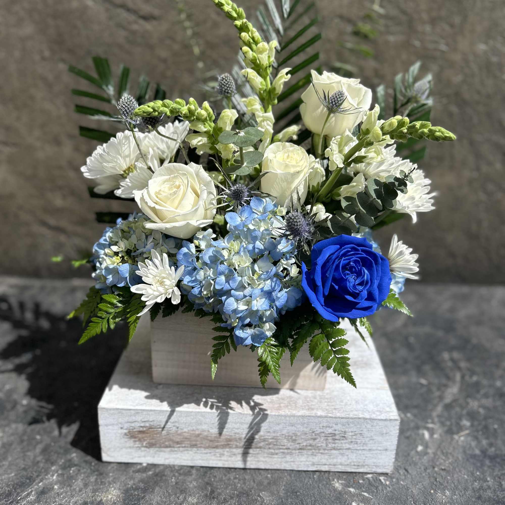 White roses, chrysanthemums, snapdragon, hydrangea, with other filler blooms, and foliage. 
This
