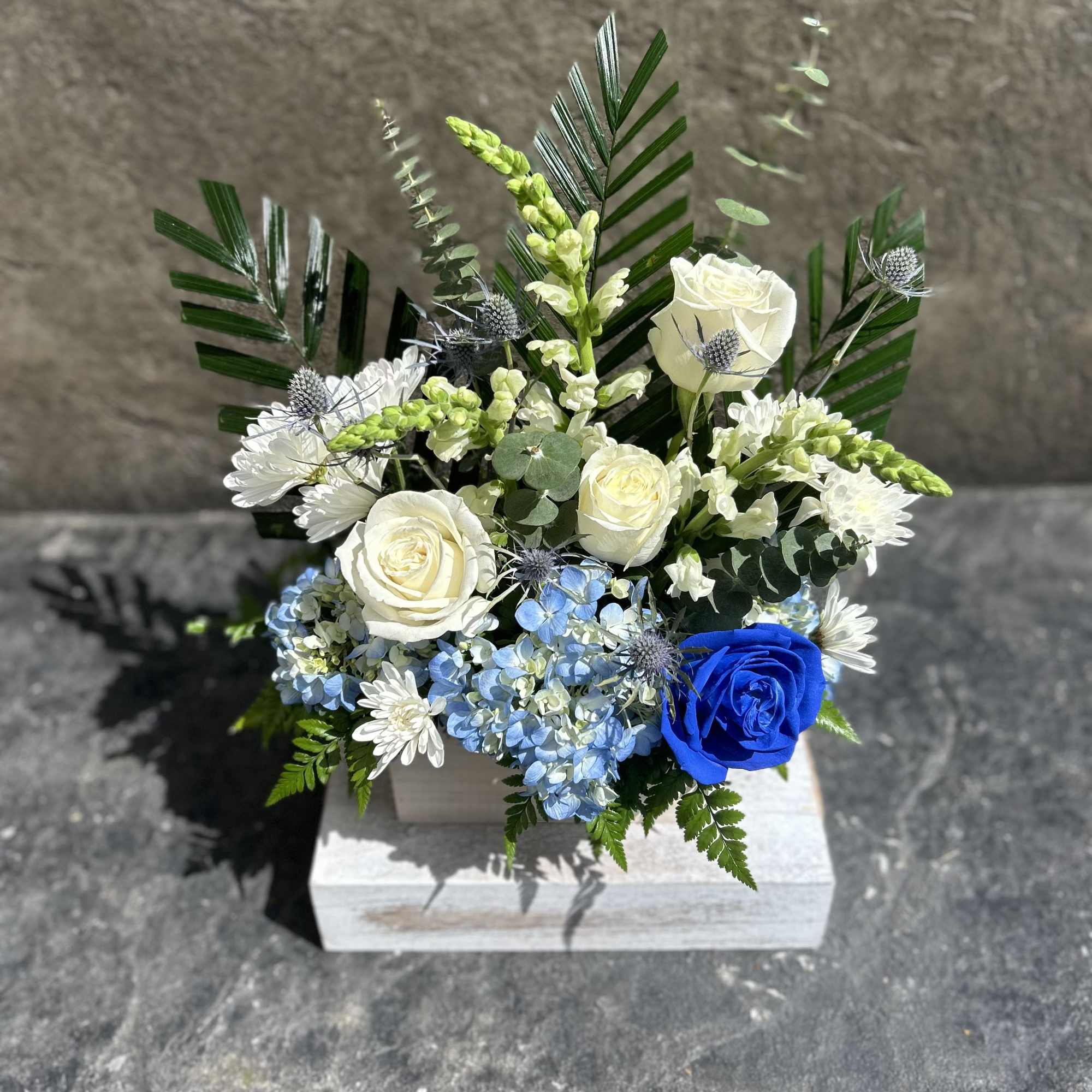 White roses, chrysanthemums, snapdragon, hydrangea, with other filler blooms, and foliage. 
This