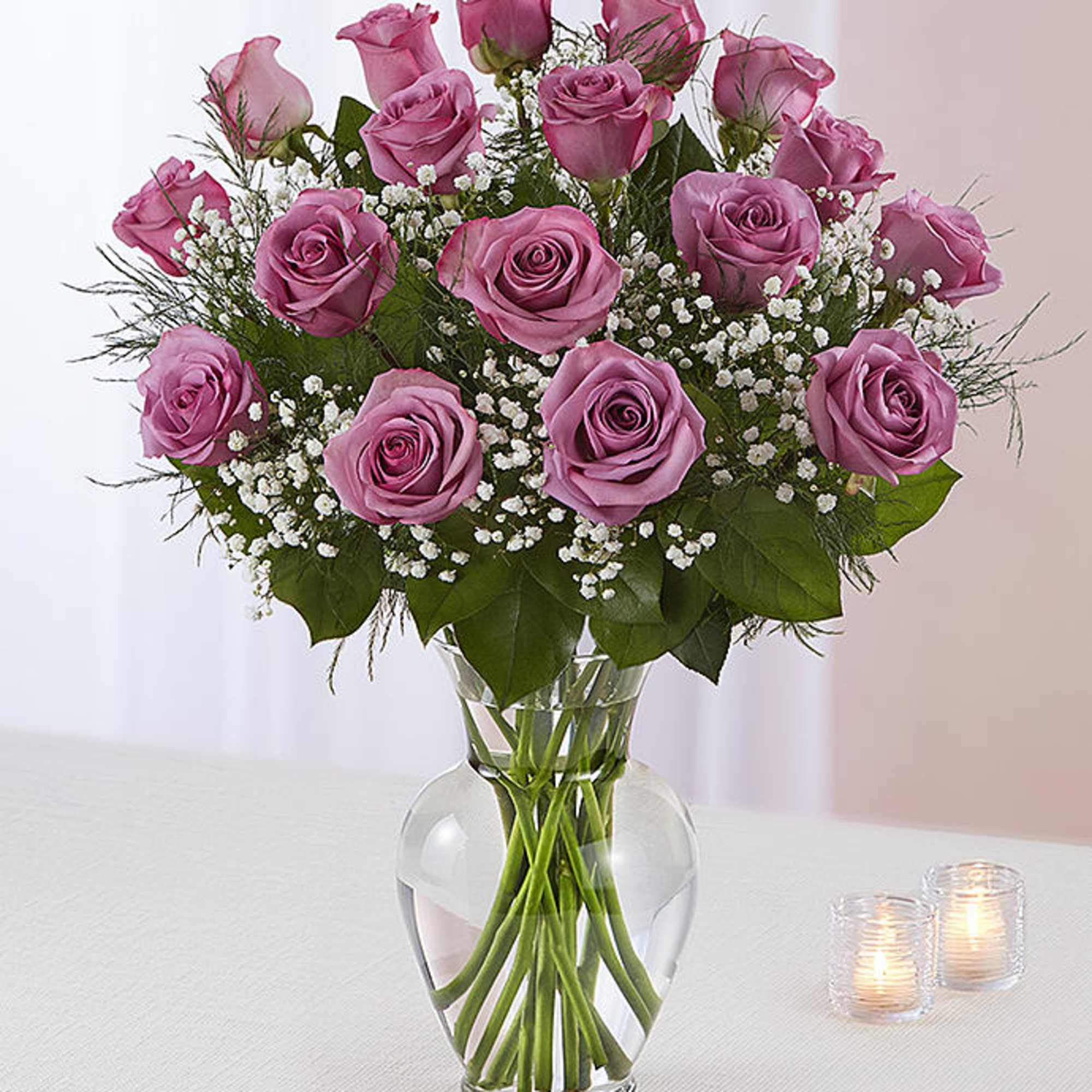 Dozen lavender roses in a glass vase with a nice greenery 
