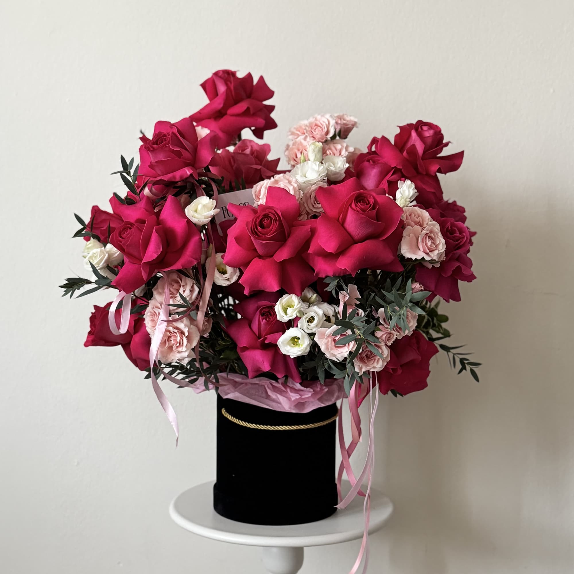 A bold, glam hatbox arrangement packed with hot pink roses, soft blush