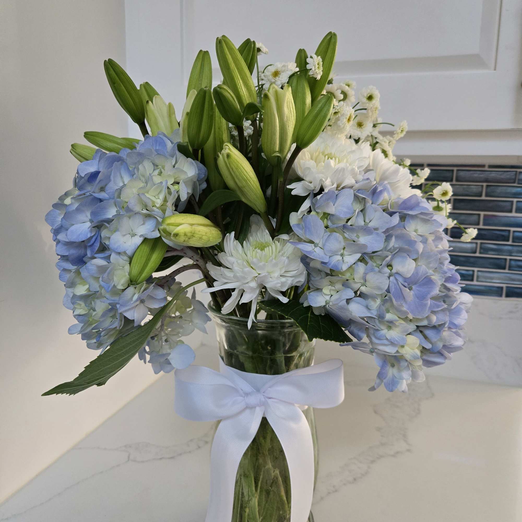 Contains 20 stems of white and blue blooms. 
Displayed in a clear