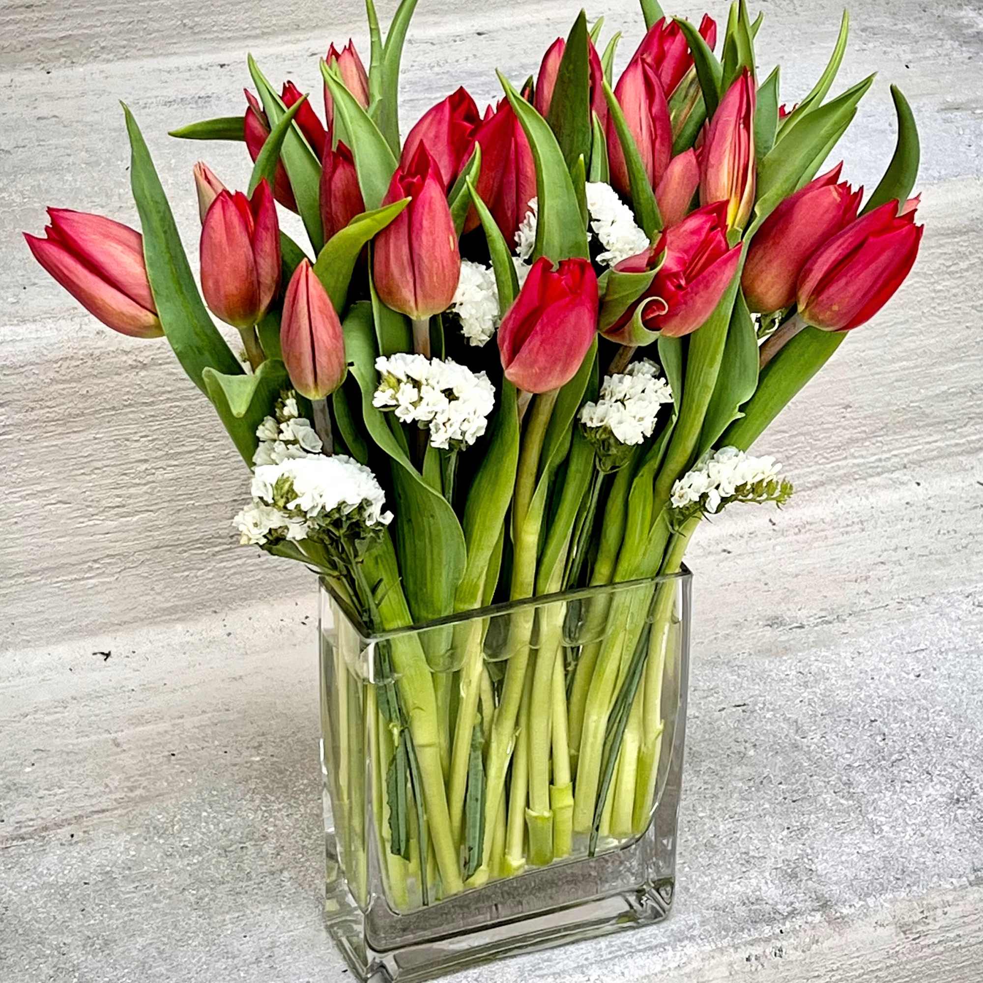 20 stems of tulips beautifully laid out in a 6x6x2in glass vase.