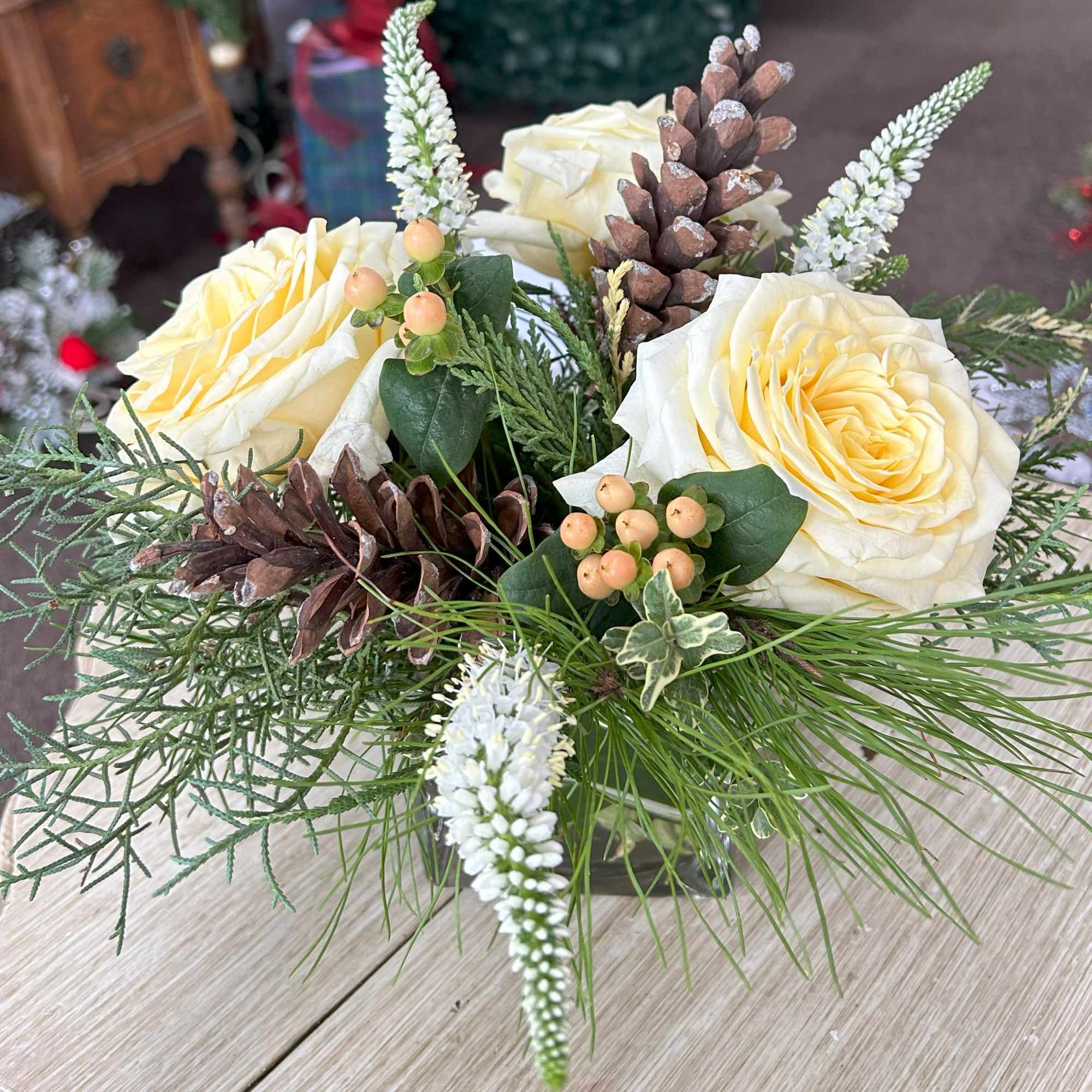 4" Cube with Christmas greens, white roses, veronica, hypericum berries, and pinecones.