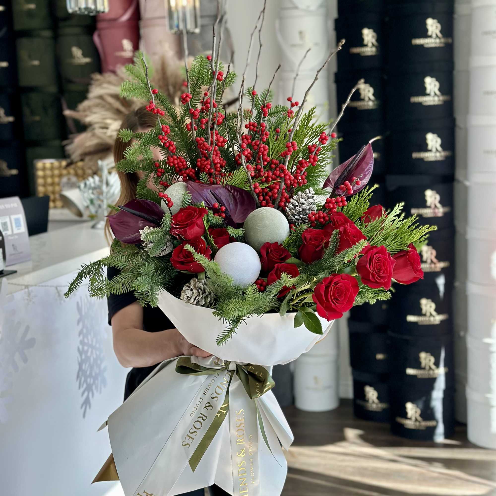 A festive winter bouquet combining classic red roses with vibrant berry branches