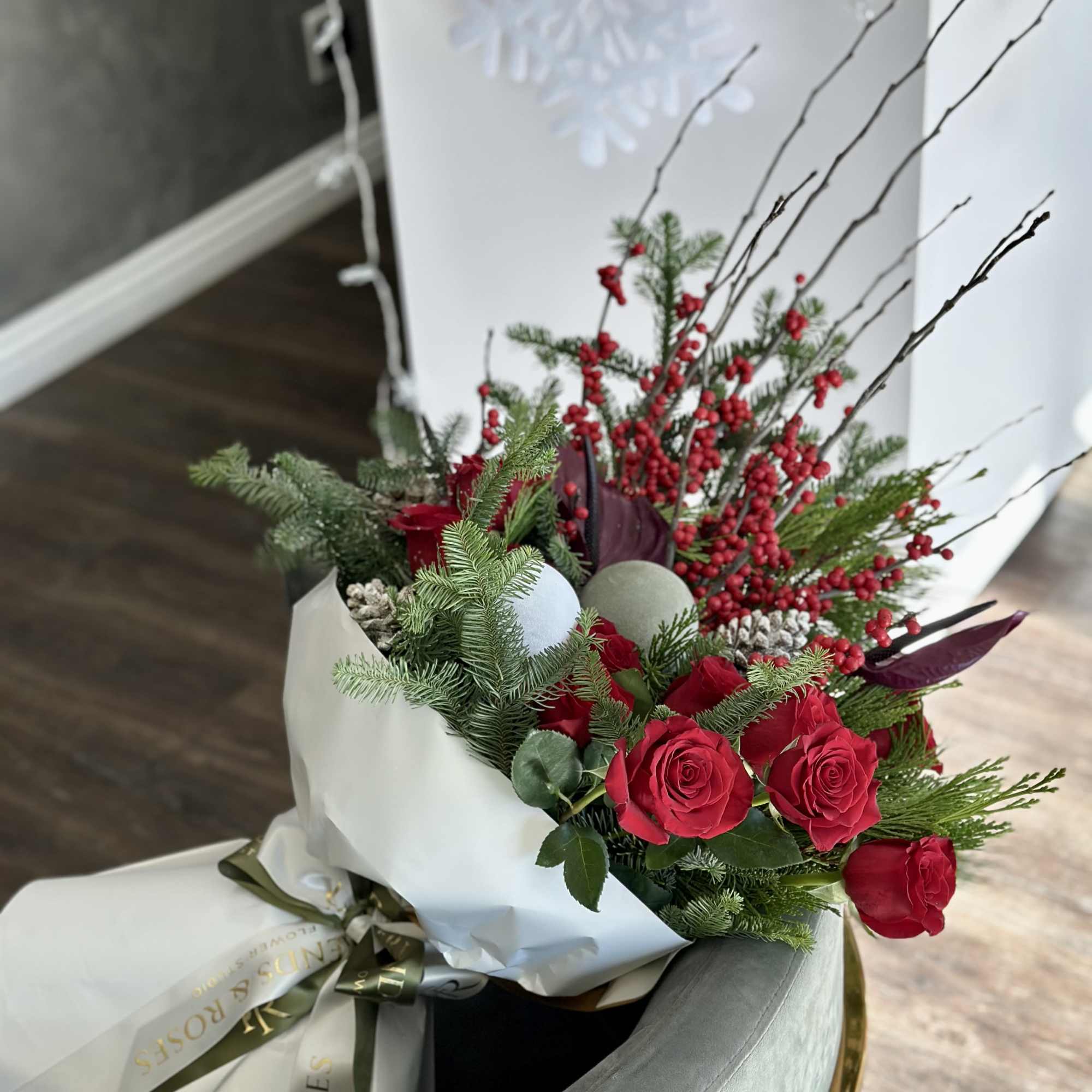 A festive winter bouquet combining classic red roses with vibrant berry branches