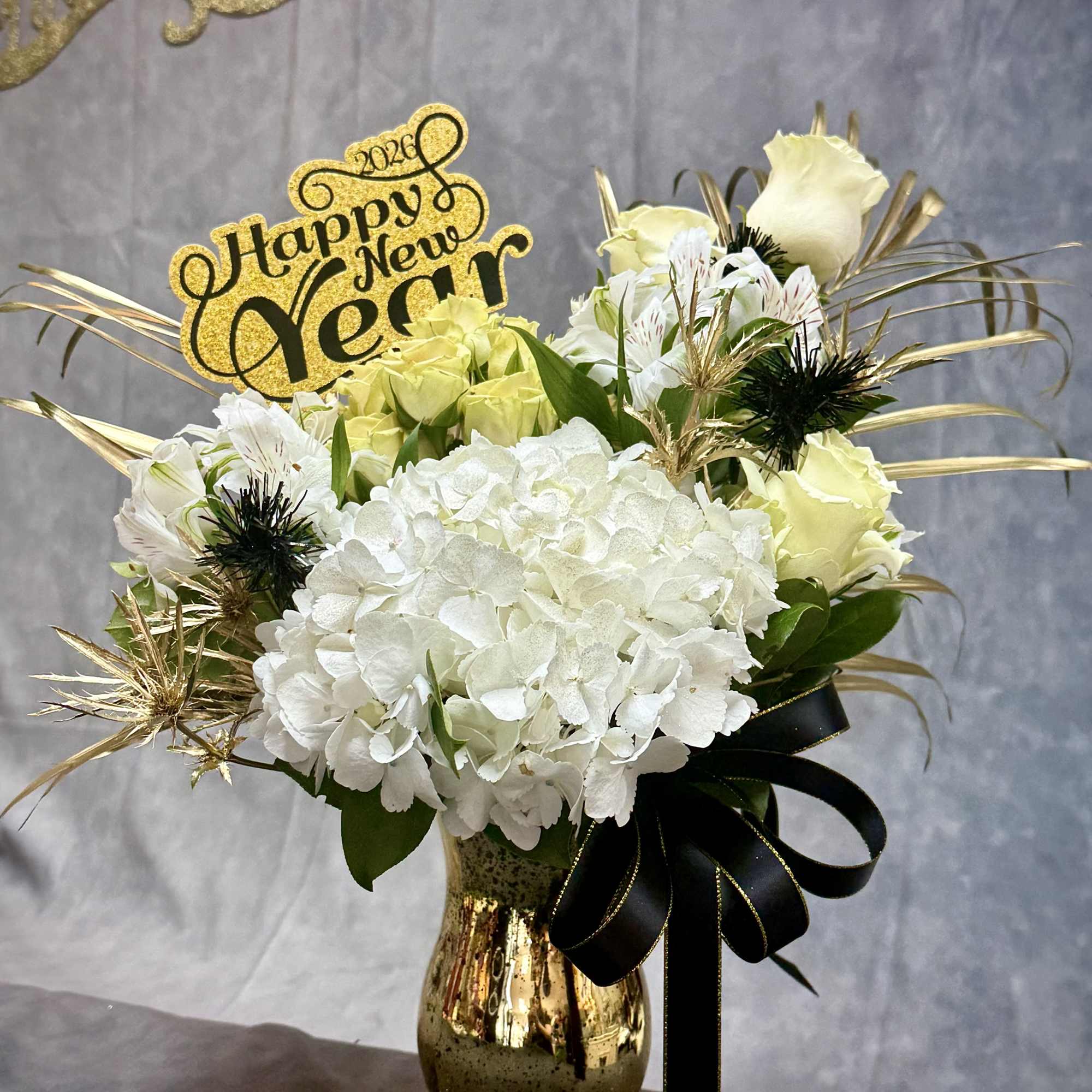 A sophisticated arrangement of creamy white hydrangeas, soft ivory blooms, and dramatic