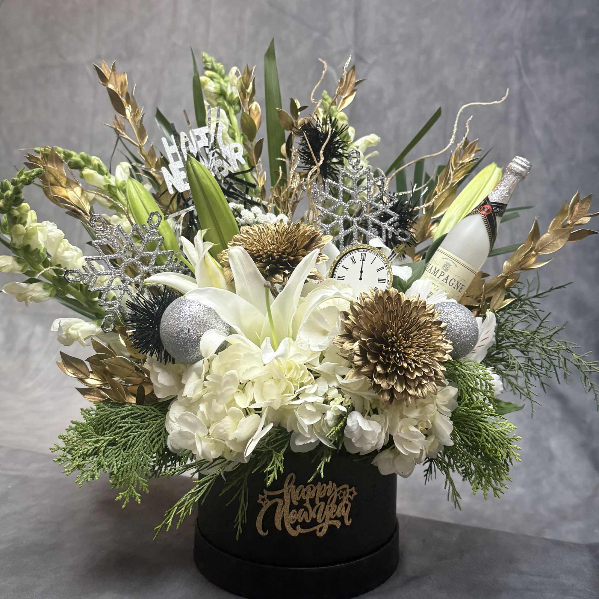 A sophisticated floral box arrangement combining soft whites, shimmering gold, and celebratory