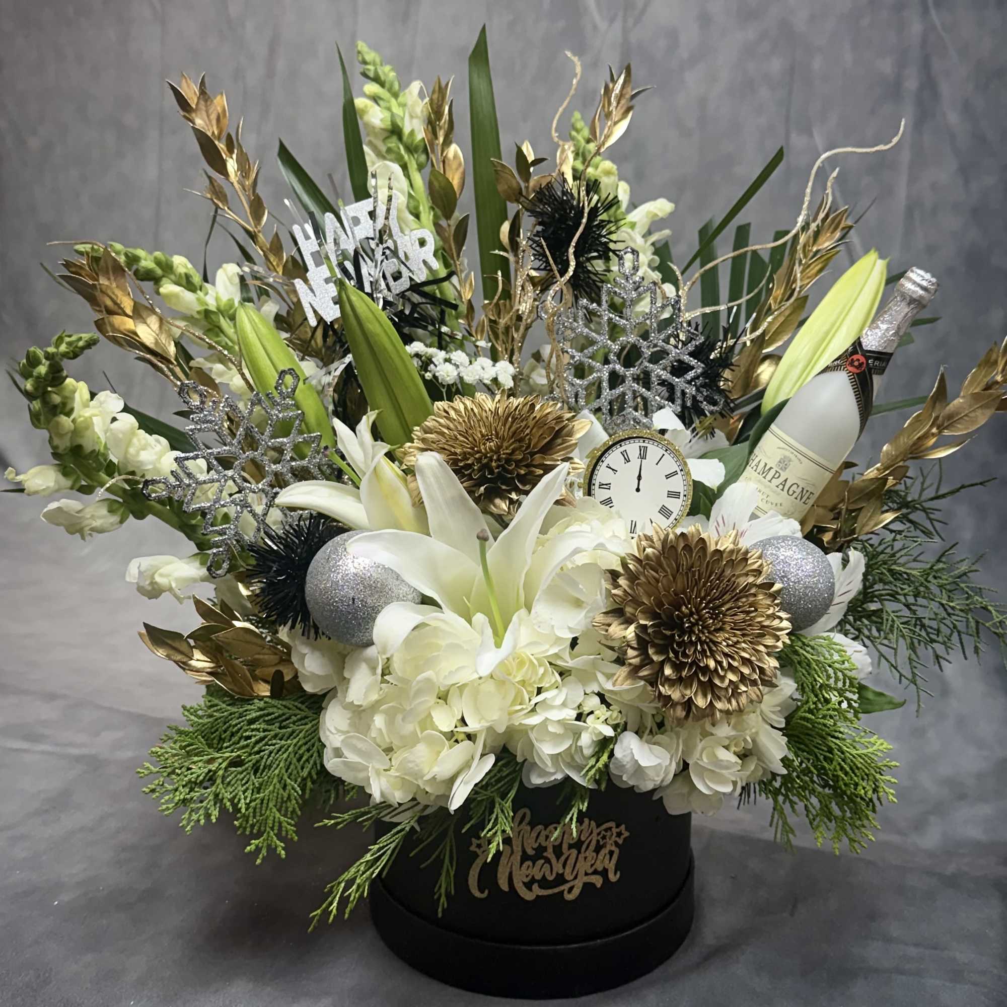 A sophisticated floral box arrangement combining soft whites, shimmering gold, and celebratory