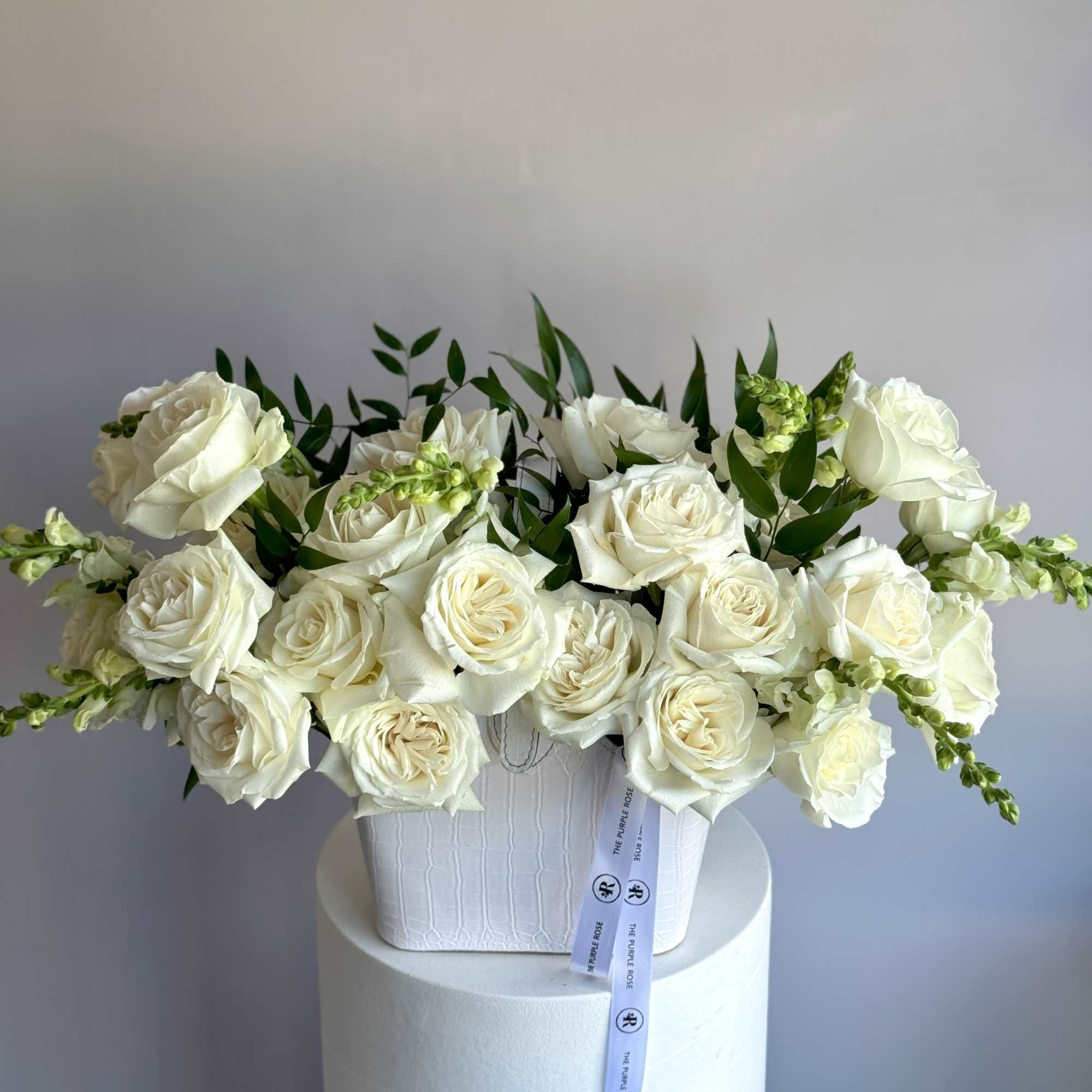 A stylish flower arrangement designed in a chic purse container, featuring premium