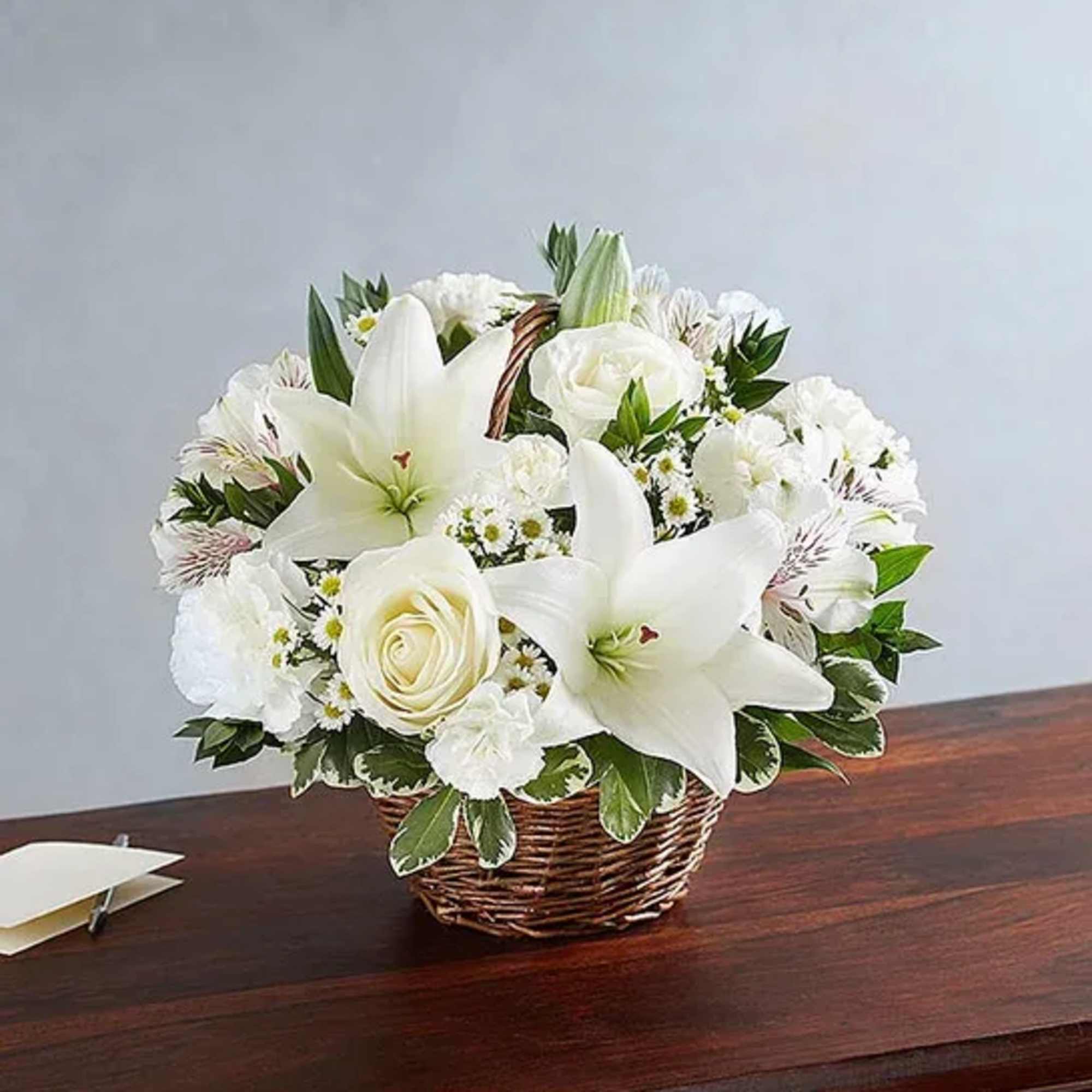 Basket arrangement of white roses, Asiatic lilies, alstroemeria, carnations, mini carnations, and
