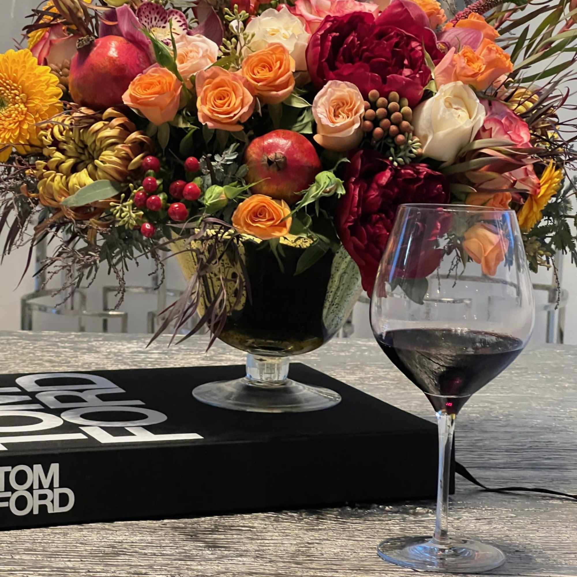 This opulent centerpiece bursts with autumnal charm, blending rich burgundy roses, golden