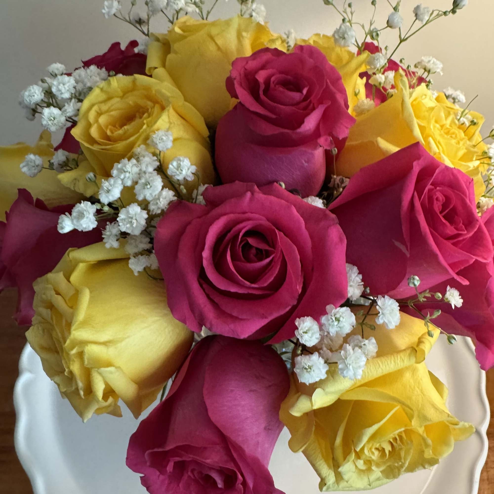 A lovely bowl of 24 colorful roses and filler brightens and lifts