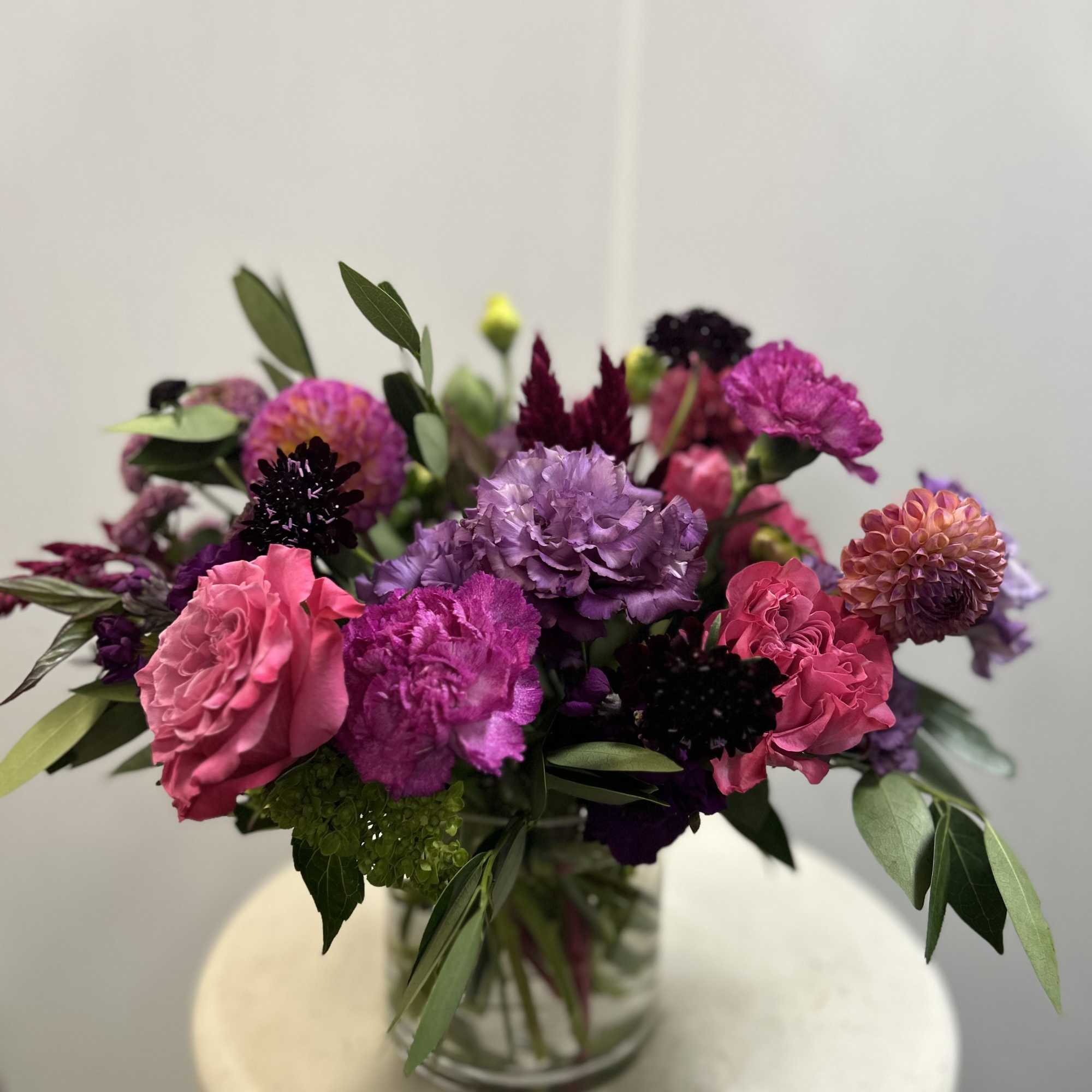 Beautiful arrangement created with rich jewel tones. Consists of roses, dahlias, lisianthus
