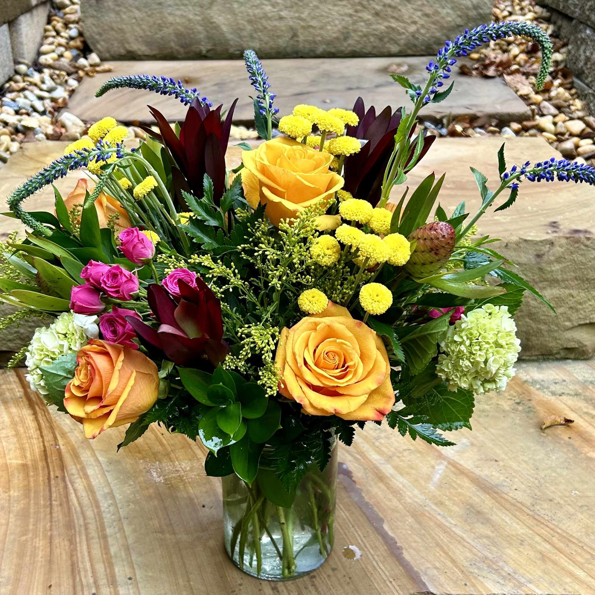 A fresh and airy arrangement of yellows, orange, pinks, purples, reds and