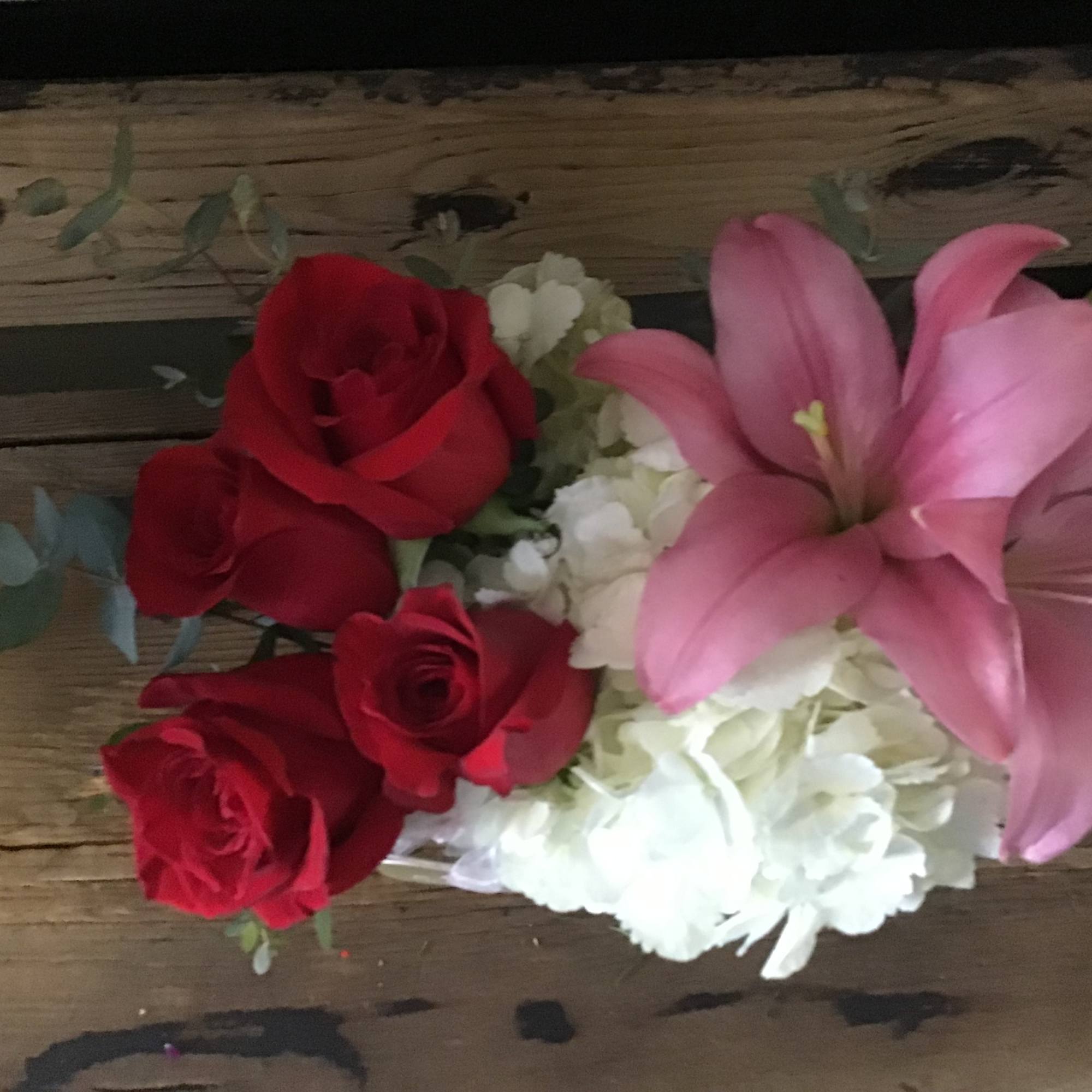 White hydrangea enveloping red roses with Lily&rsquo;s and eucalyptus with other filler