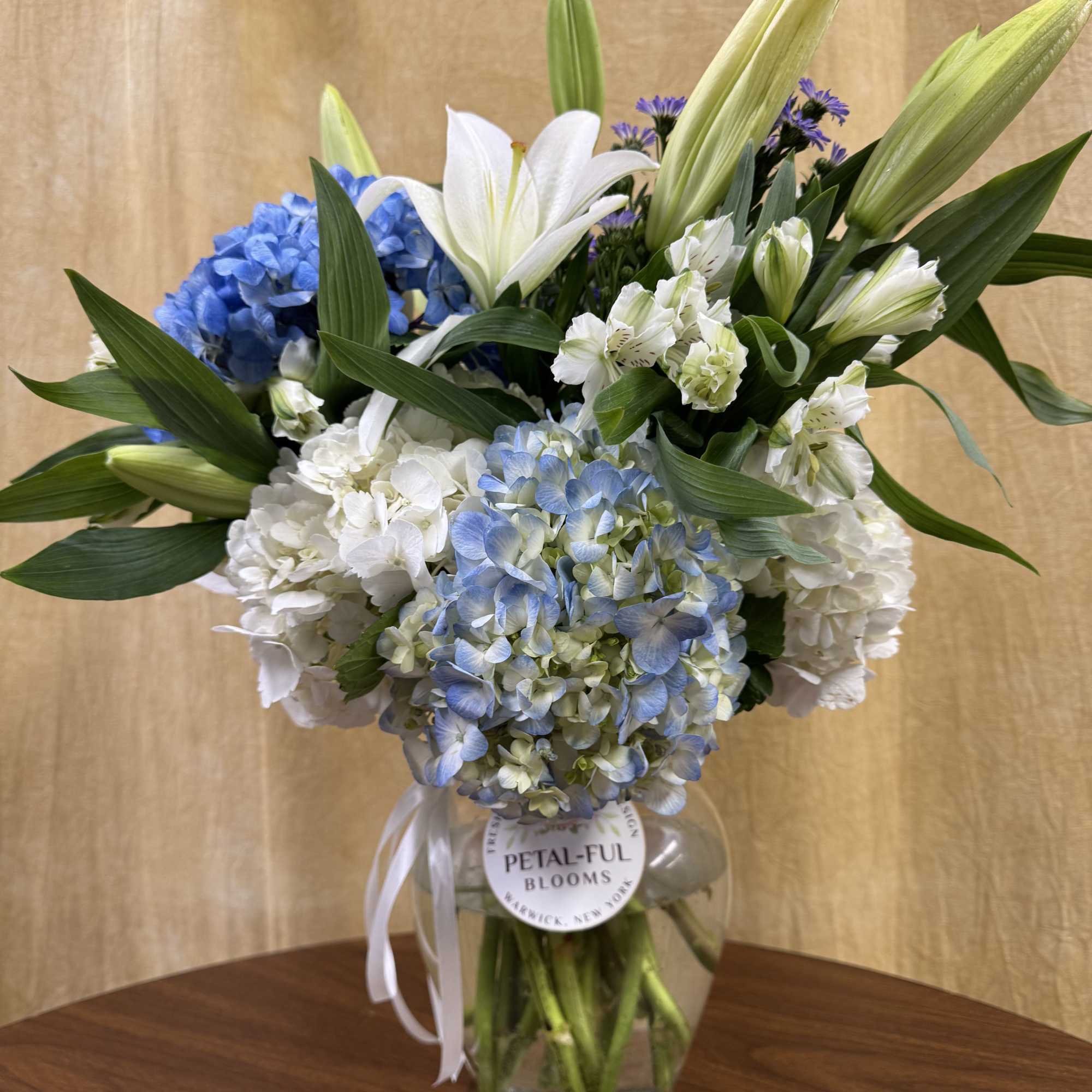 This arrangement contains asiatic lilies, hydrangeas and other seasonal blooms. It is
