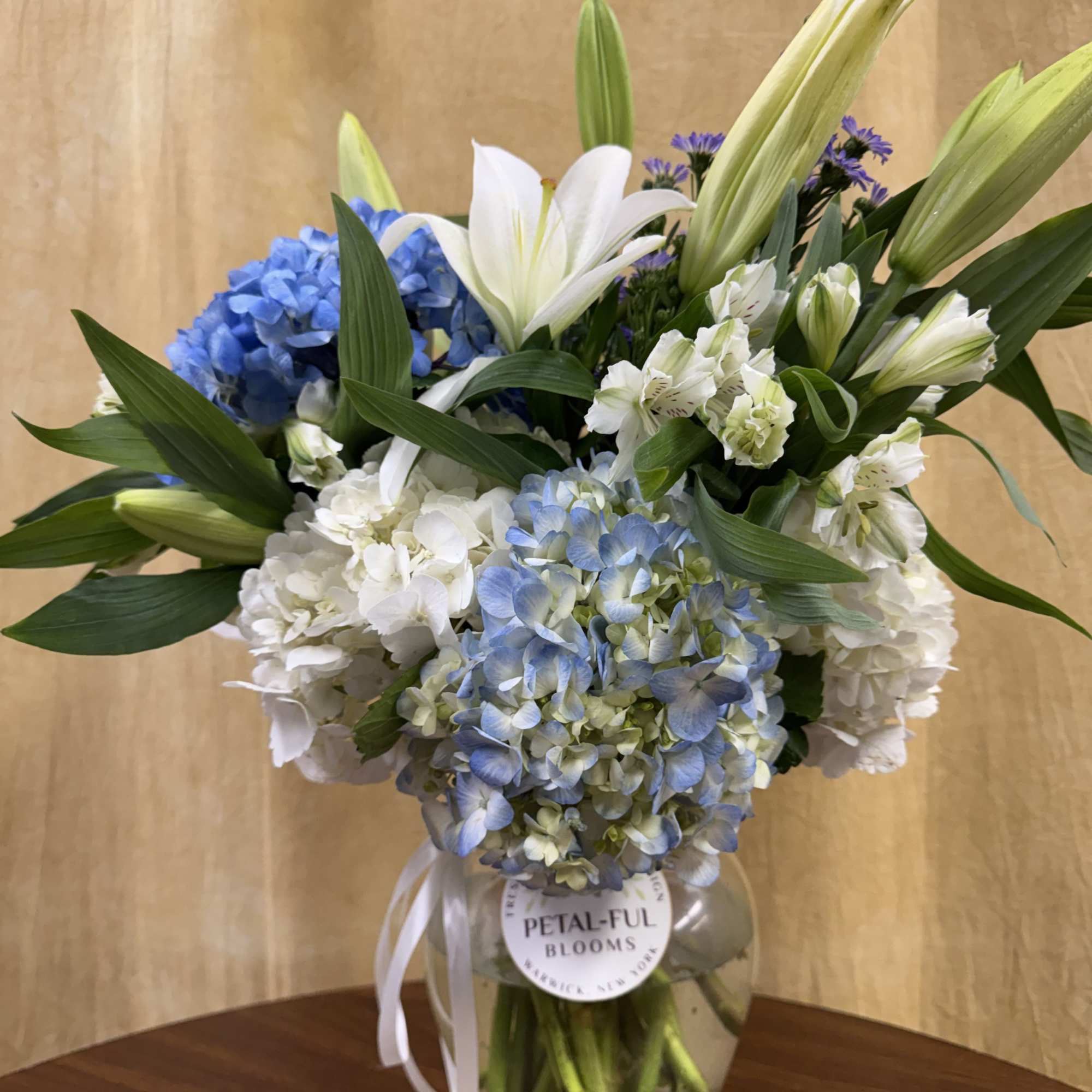 This arrangement contains asiatic lilies, hydrangeas and other seasonal blooms. It is