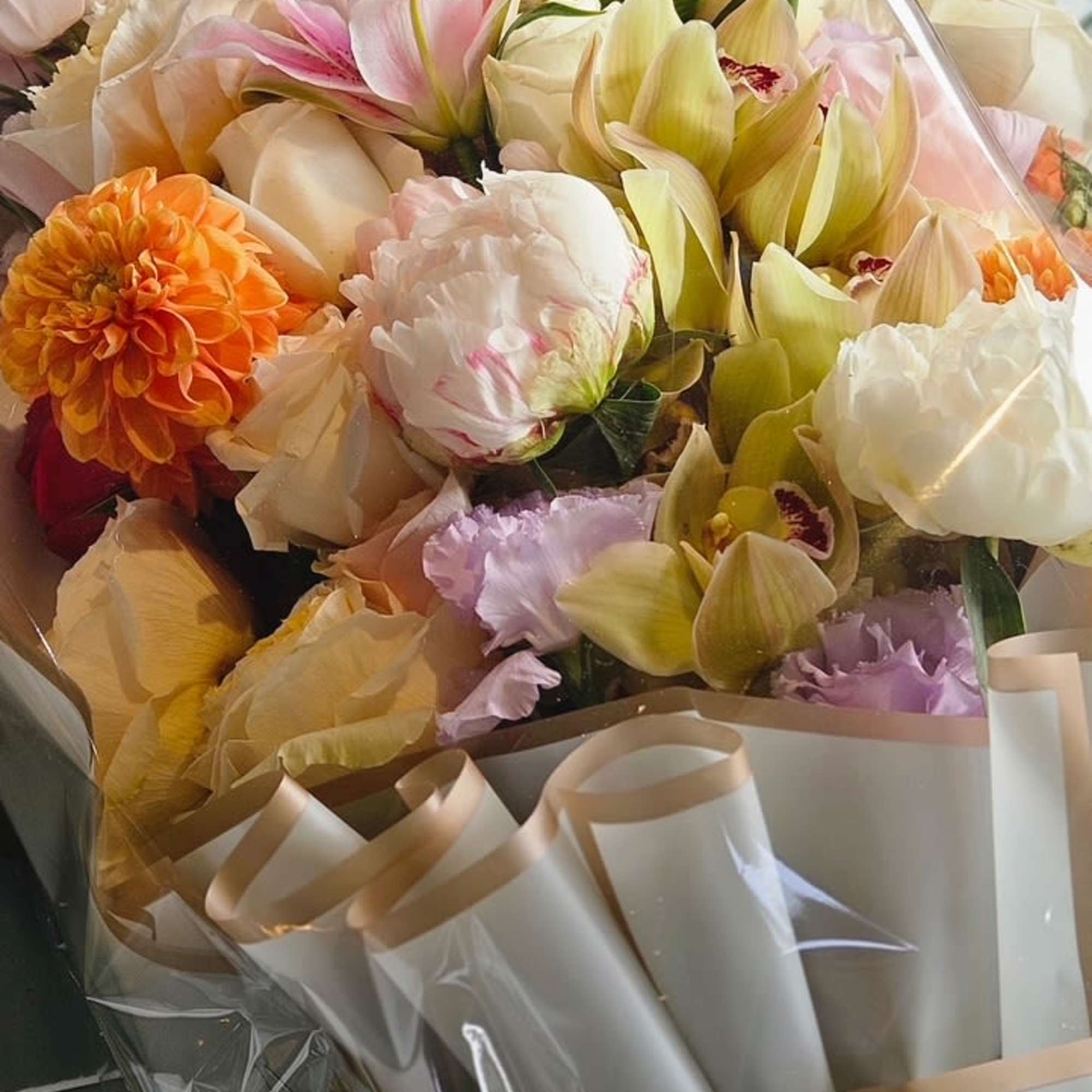 This premium wrap bouquet features dahlias, peonies, rose lilies, spray roses, cymbidium