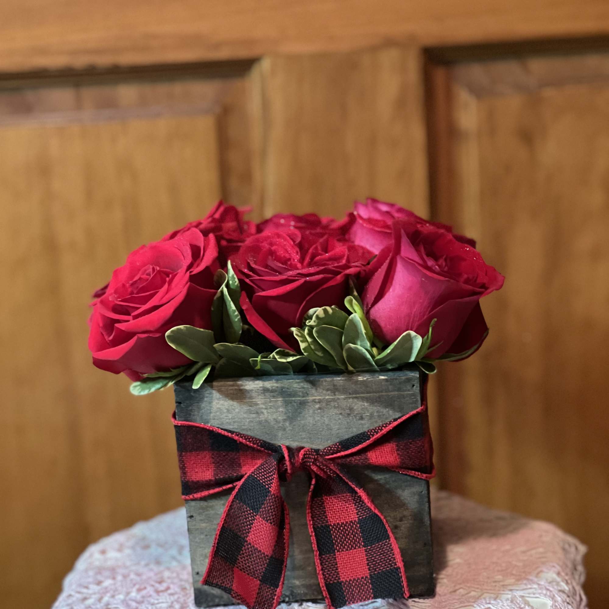 9 roses nestled into a wooden box with variegated pittosporum, finished off