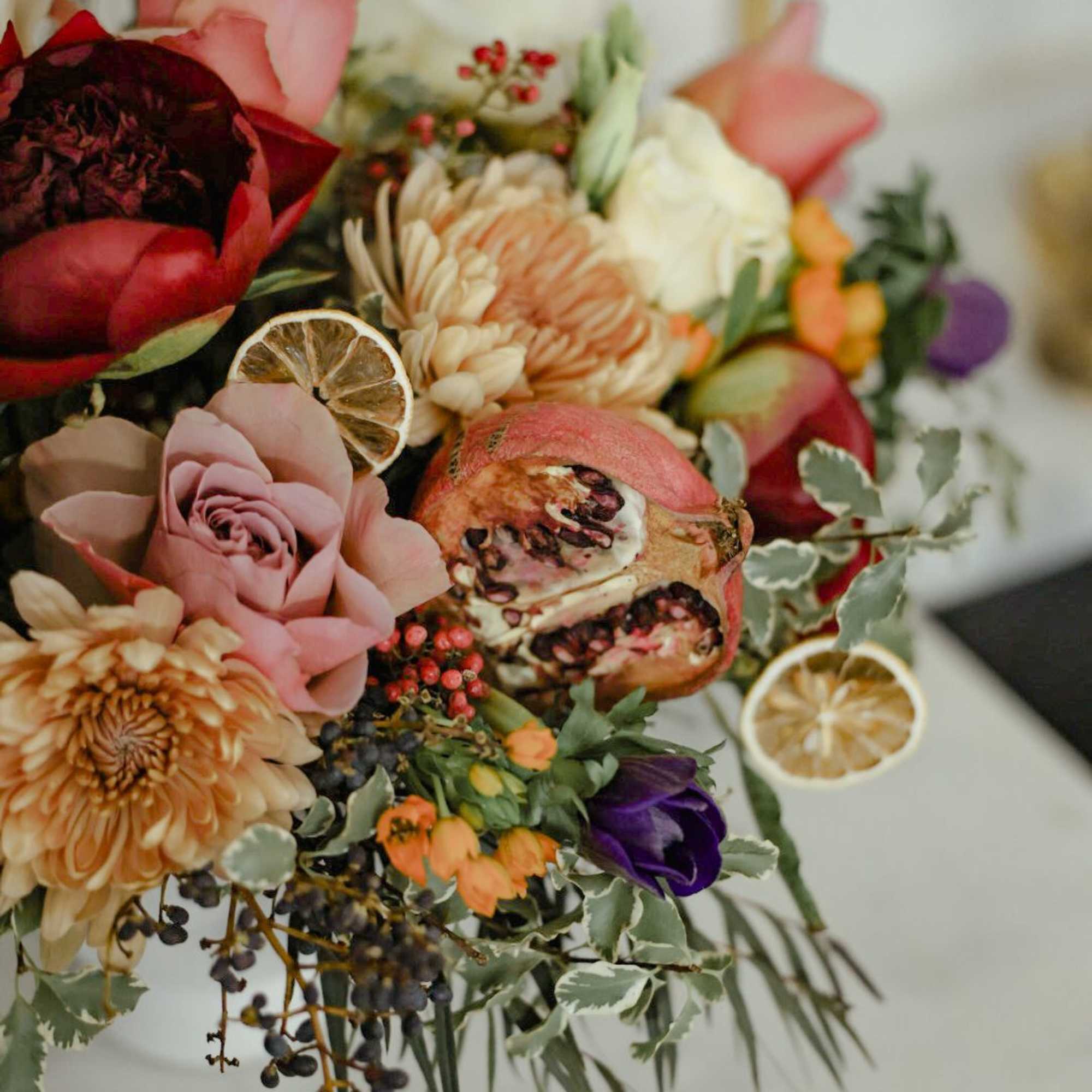 A lush and unique arrangement with berries, dried fruit, garden roses, muted